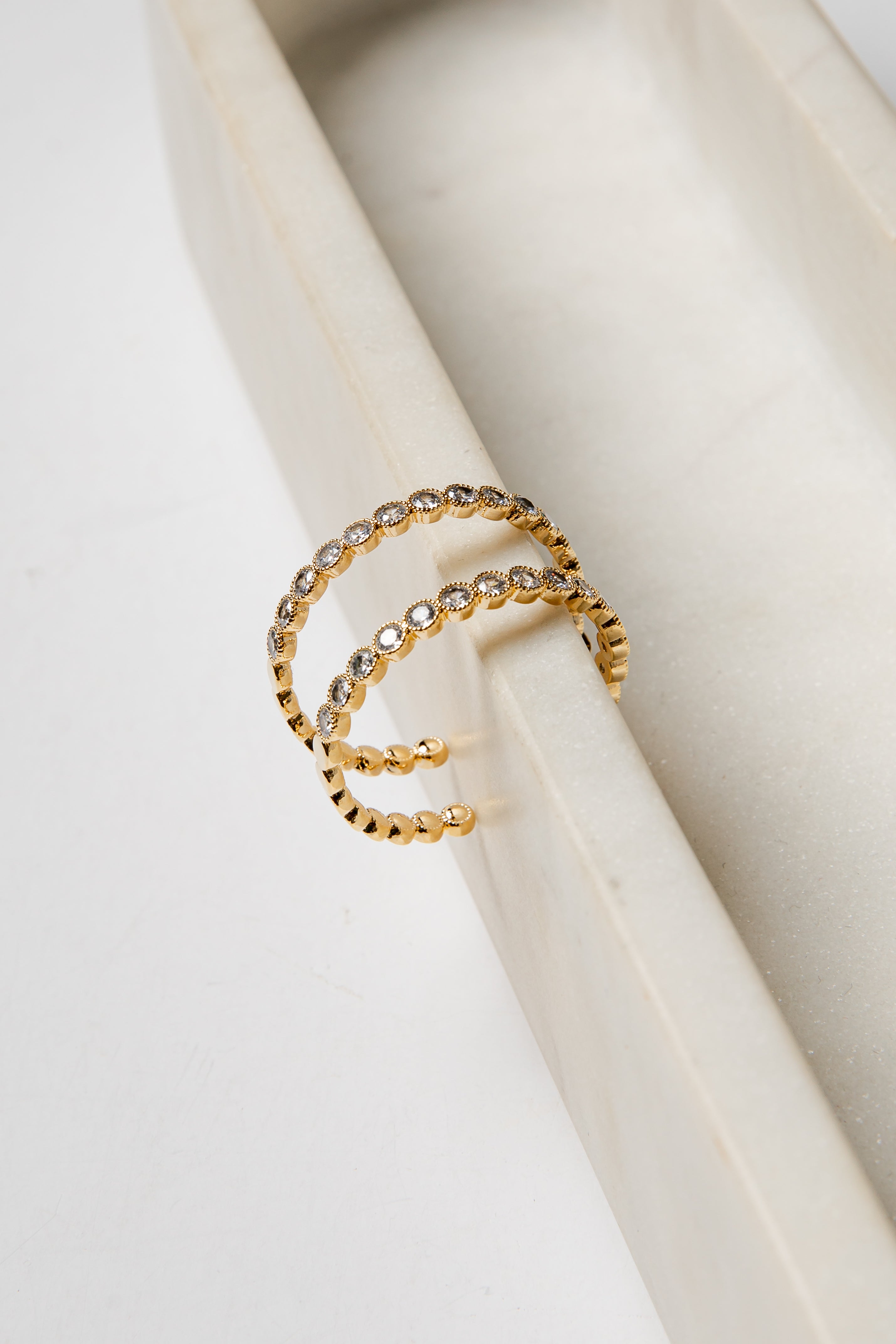 Gold earrings with embedded stones on a white surface