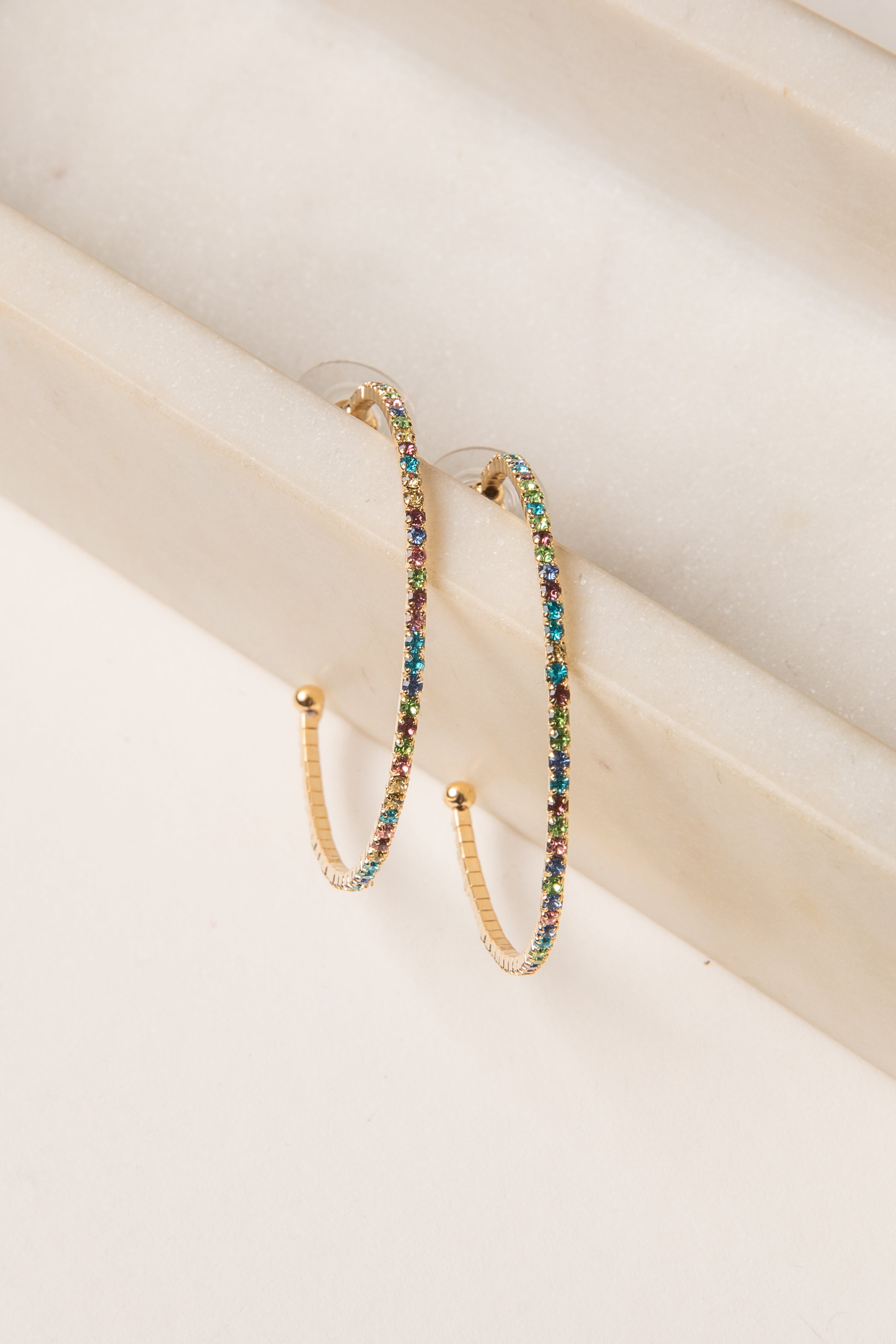 Multicolored beaded hoop earrings on a light wooden surface