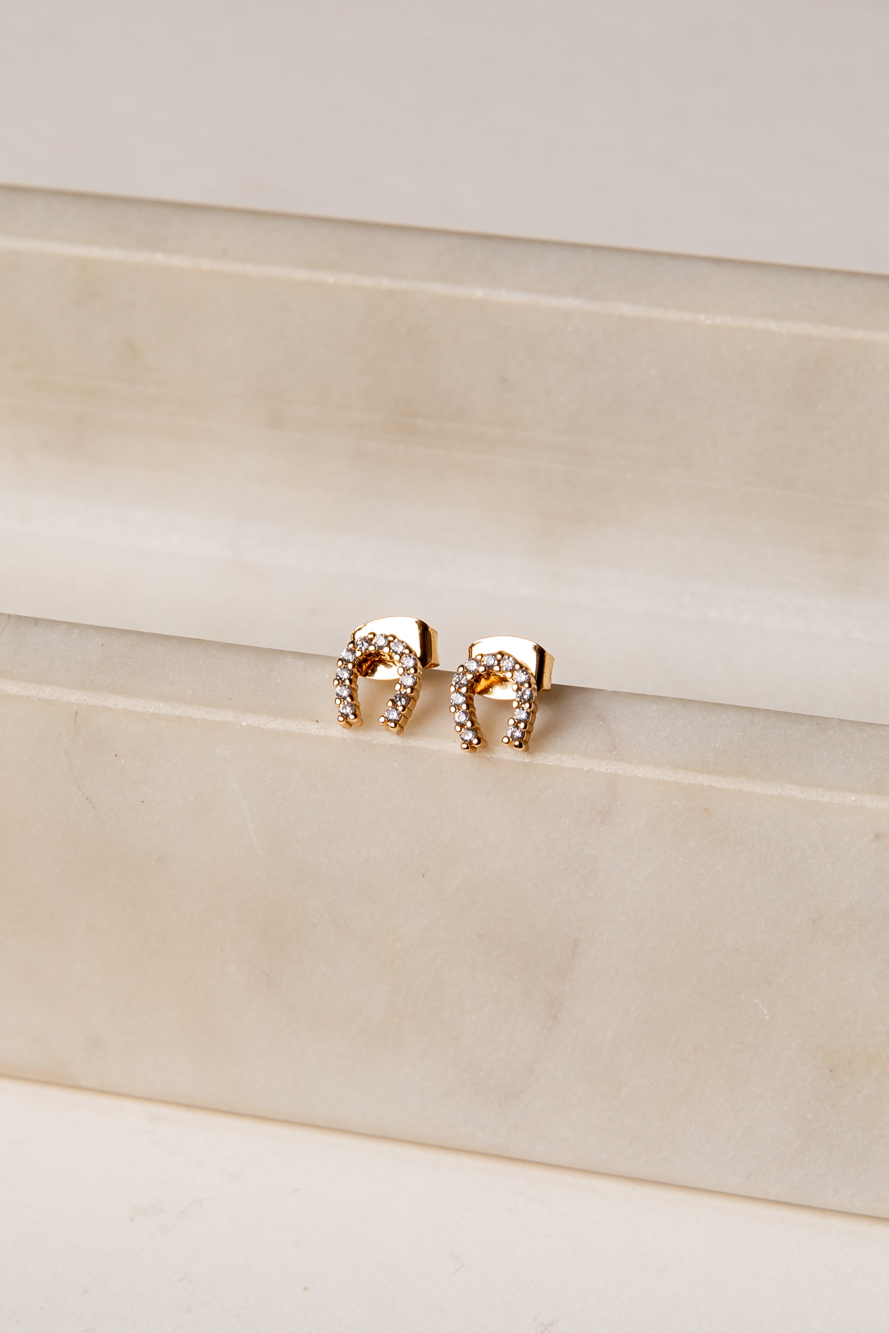 Gold earrings on a beige surface