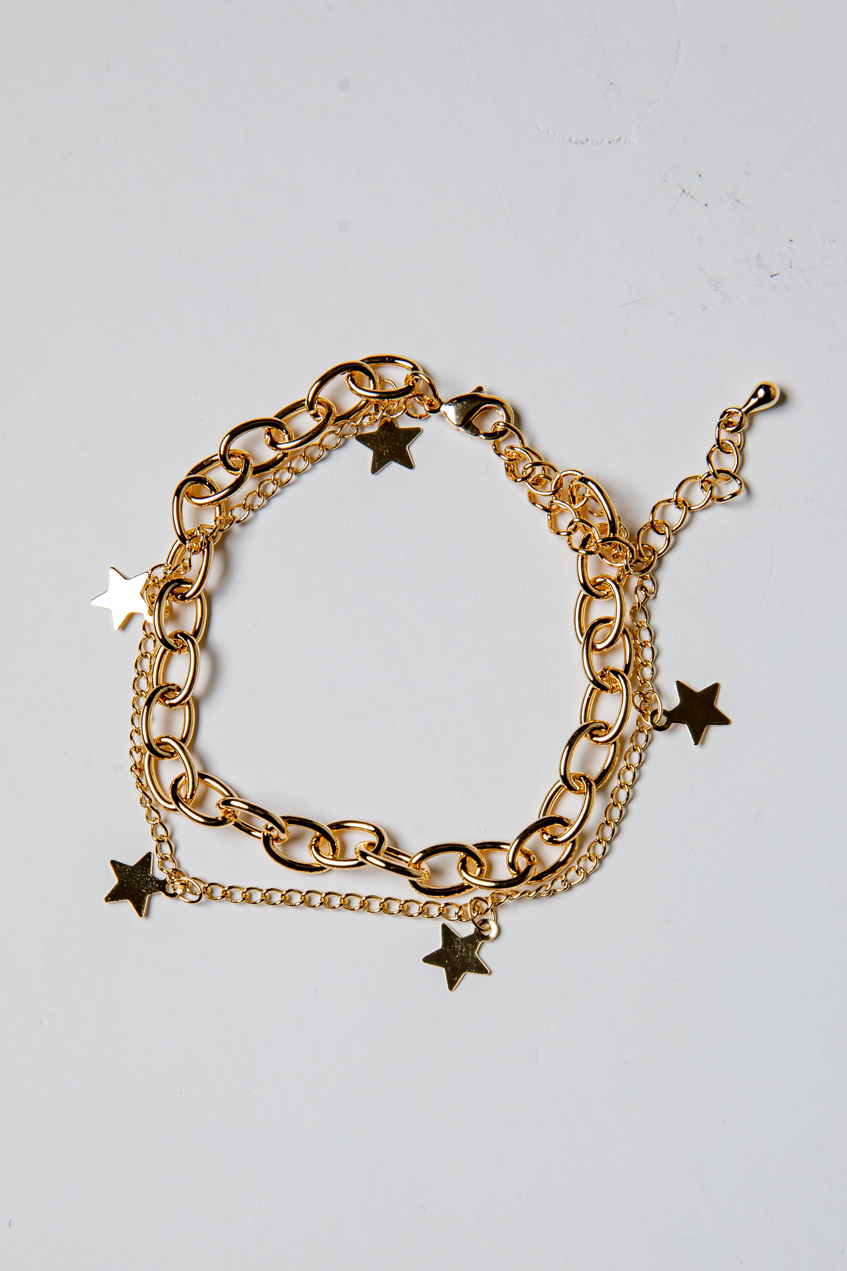 Gold chain bracelet with star charms on a light gray background