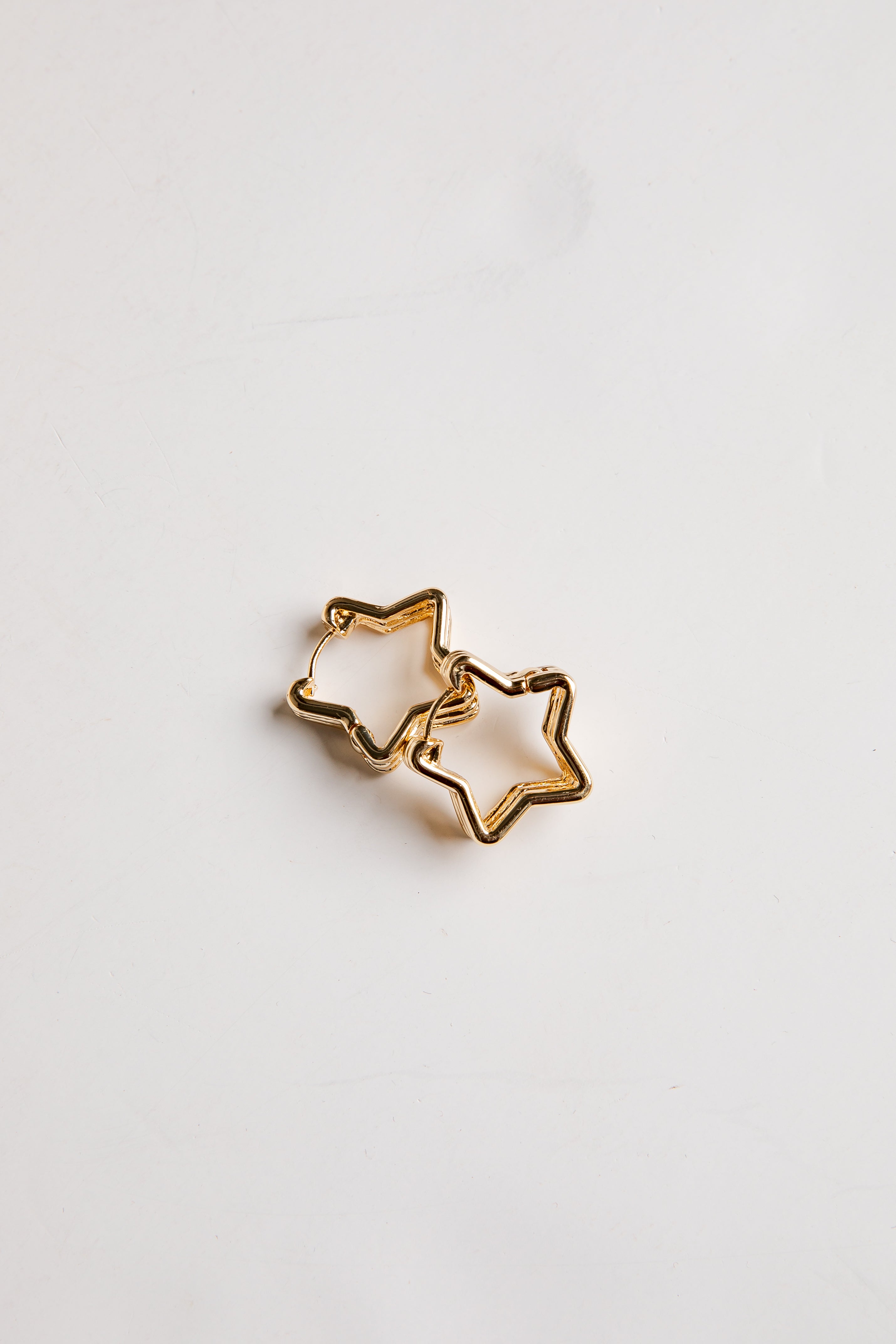 Gold star-shaped earrings on a light gray background