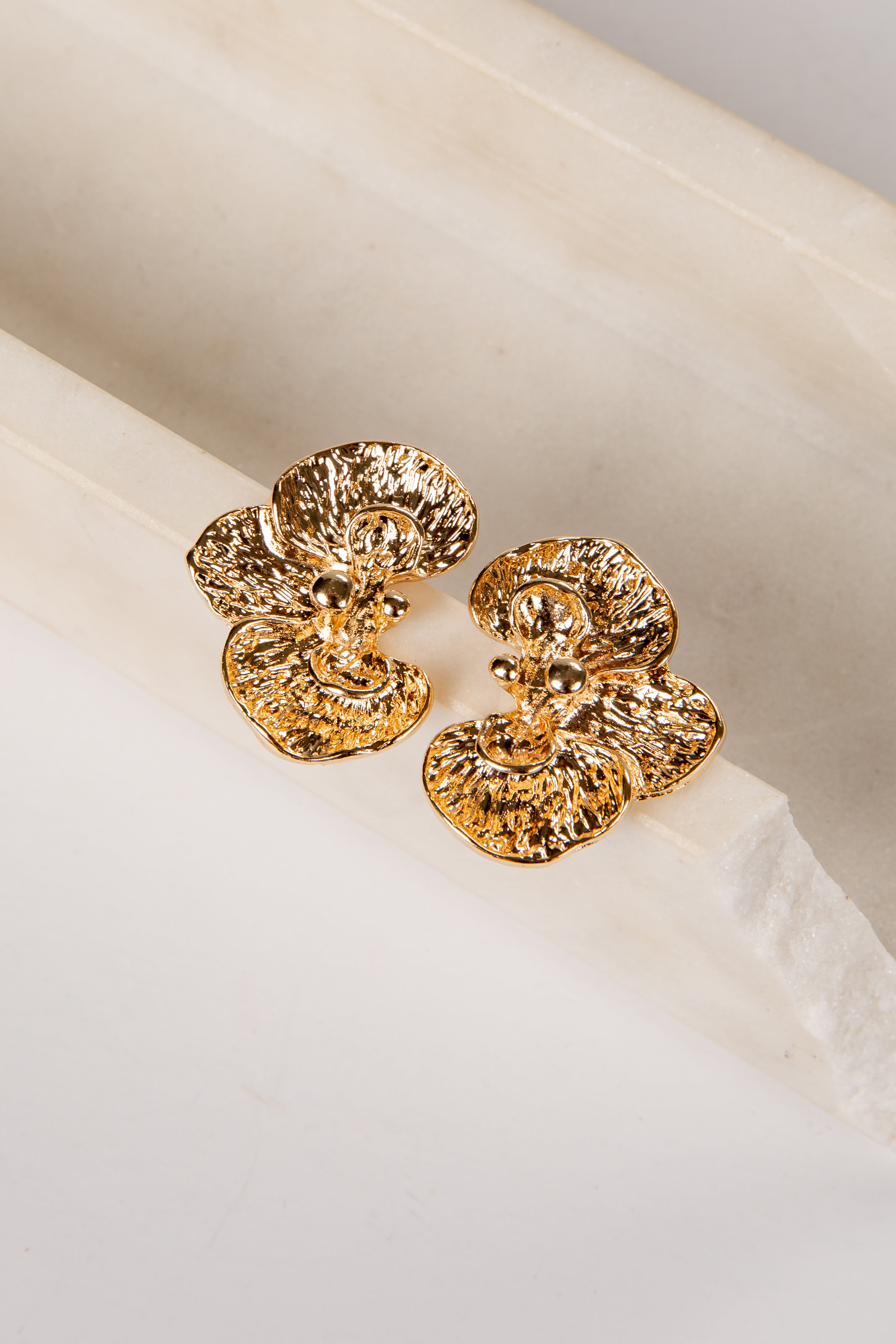 Gold earrings on a white fabric background