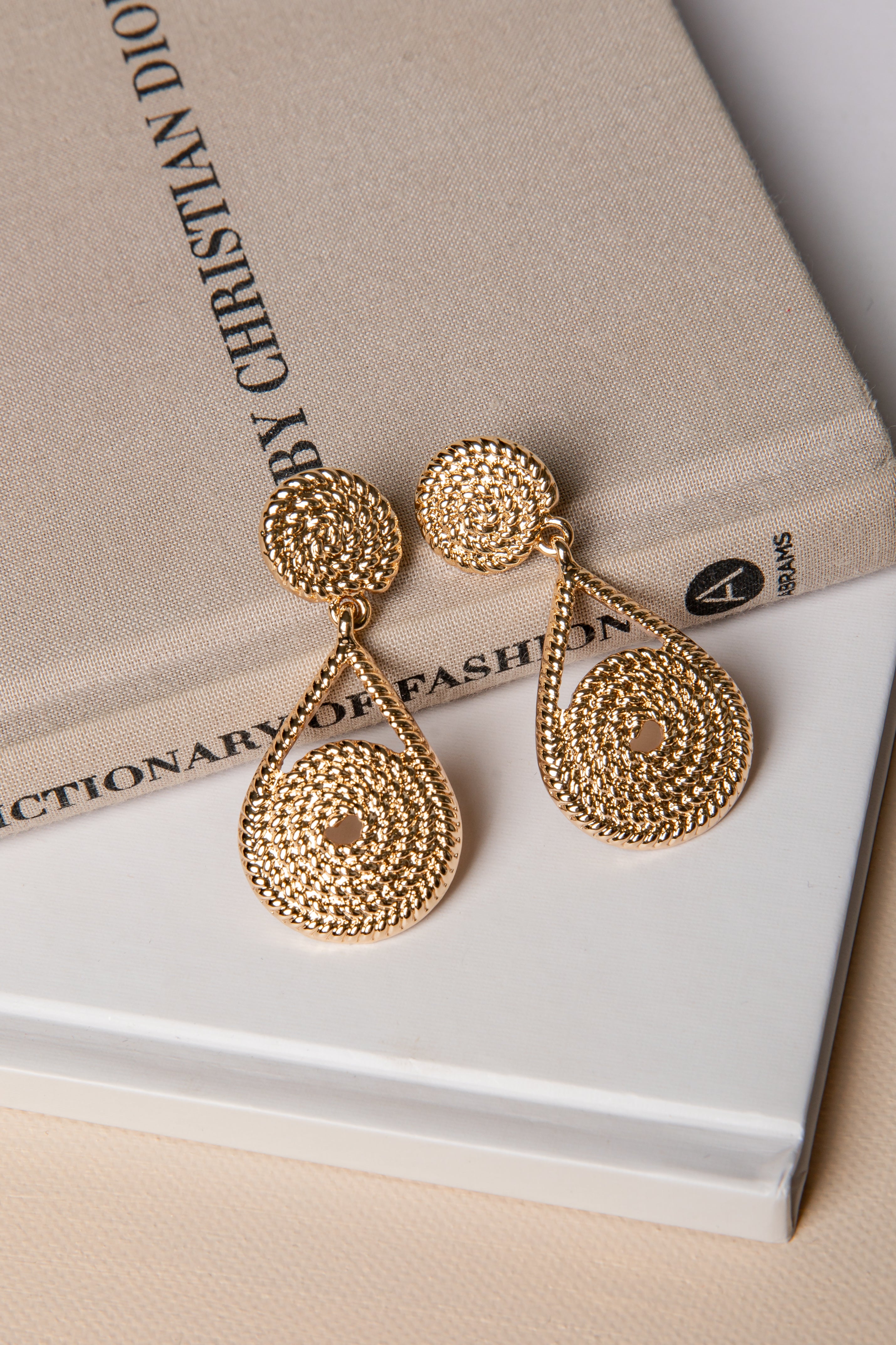 Gold earrings on a book with &