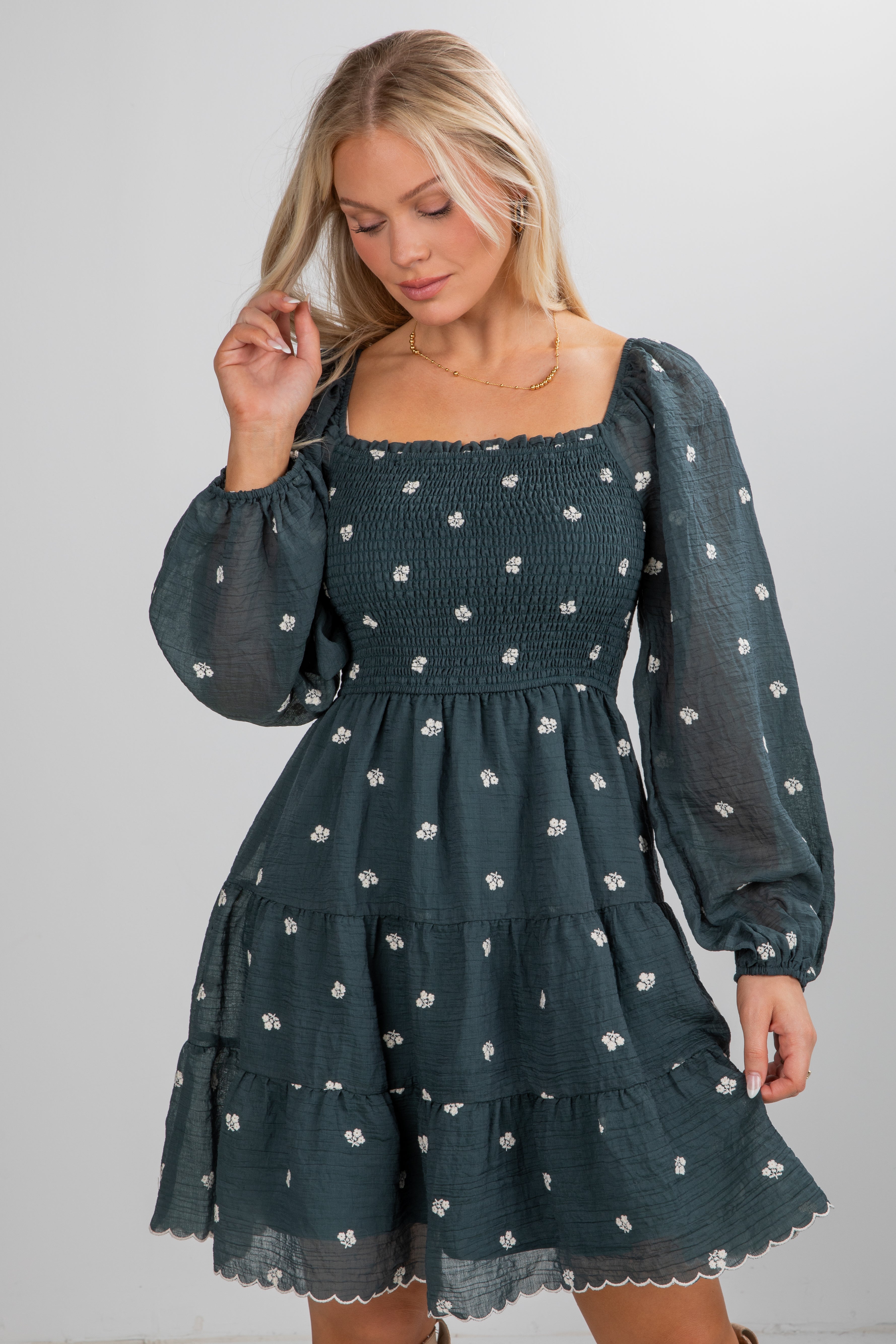 Woman wearing a dark green dress with floral pattern on a plain background