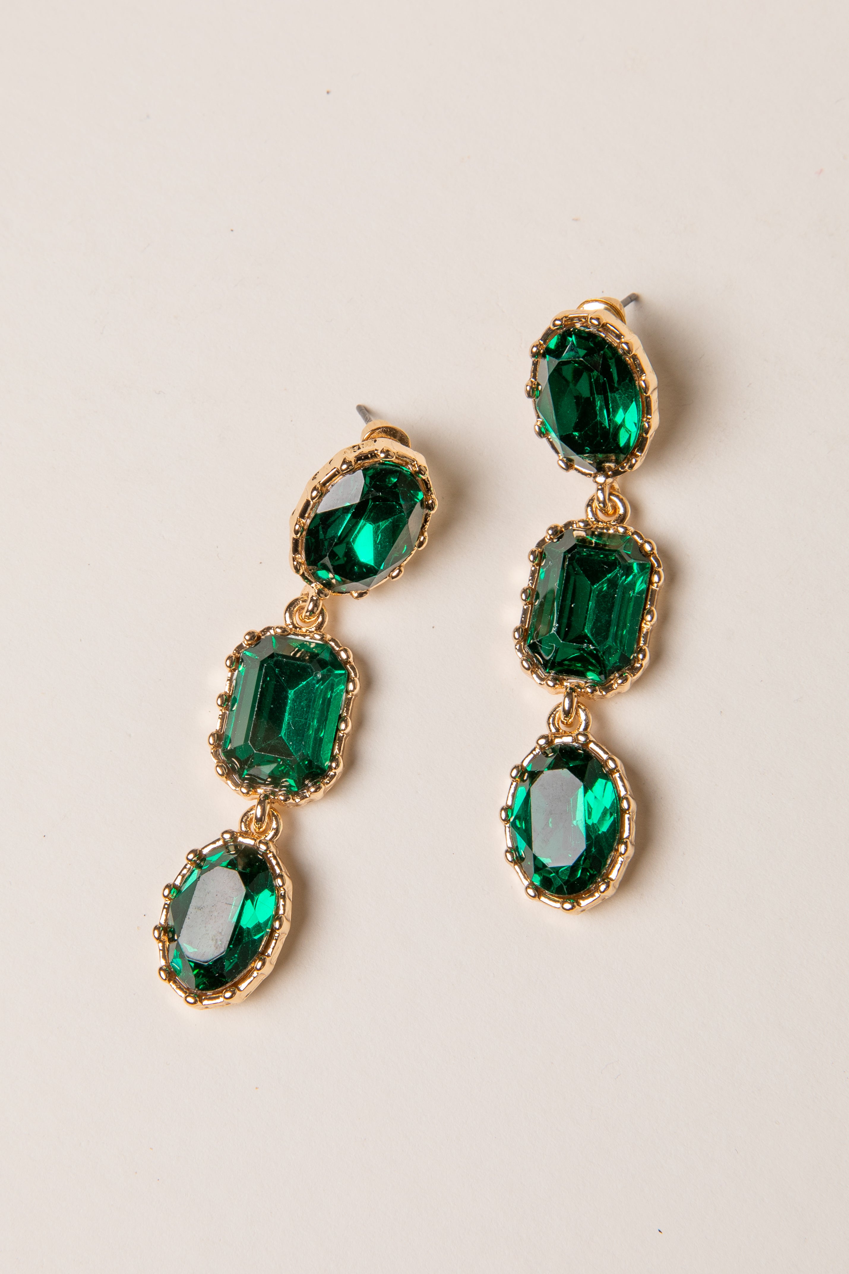 Green gemstone earrings with gold accents on a light background