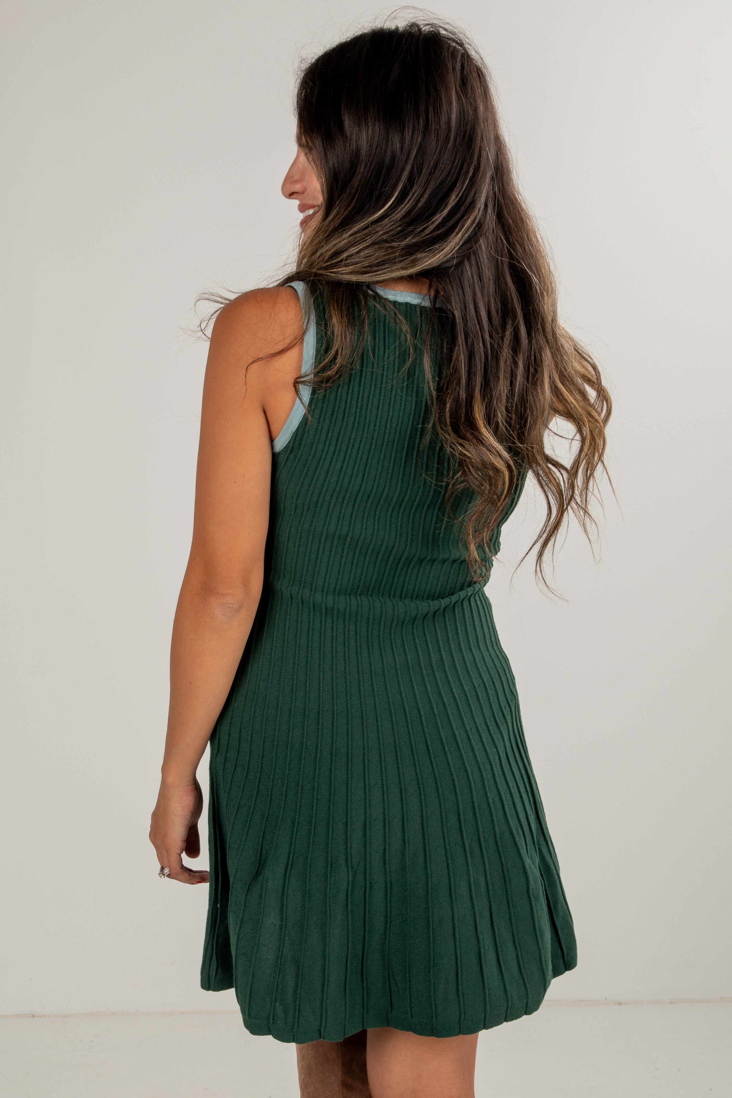 Woman wearing a green ribbed dress against a white background