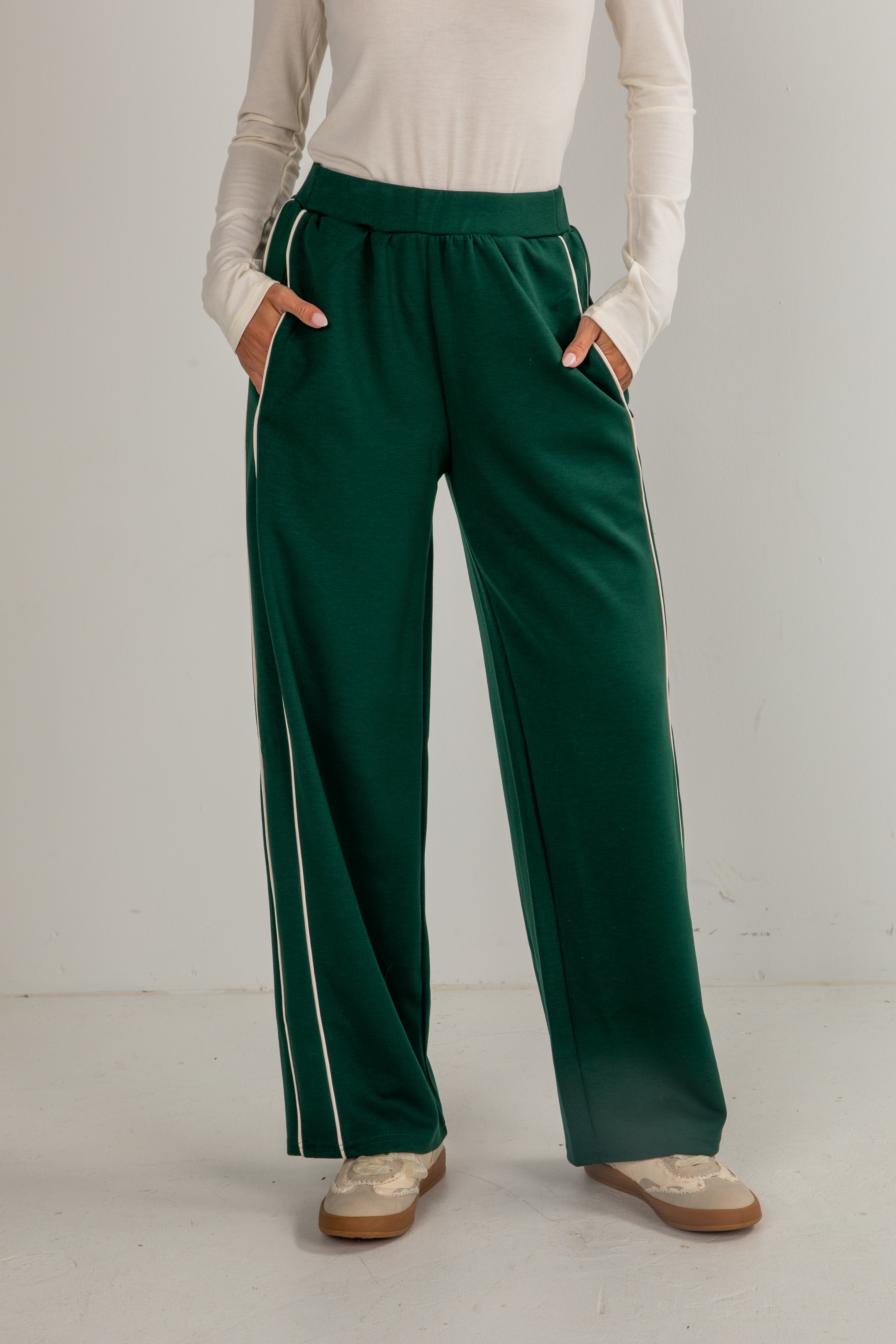 Person wearing green pants with white stripes on a plain background