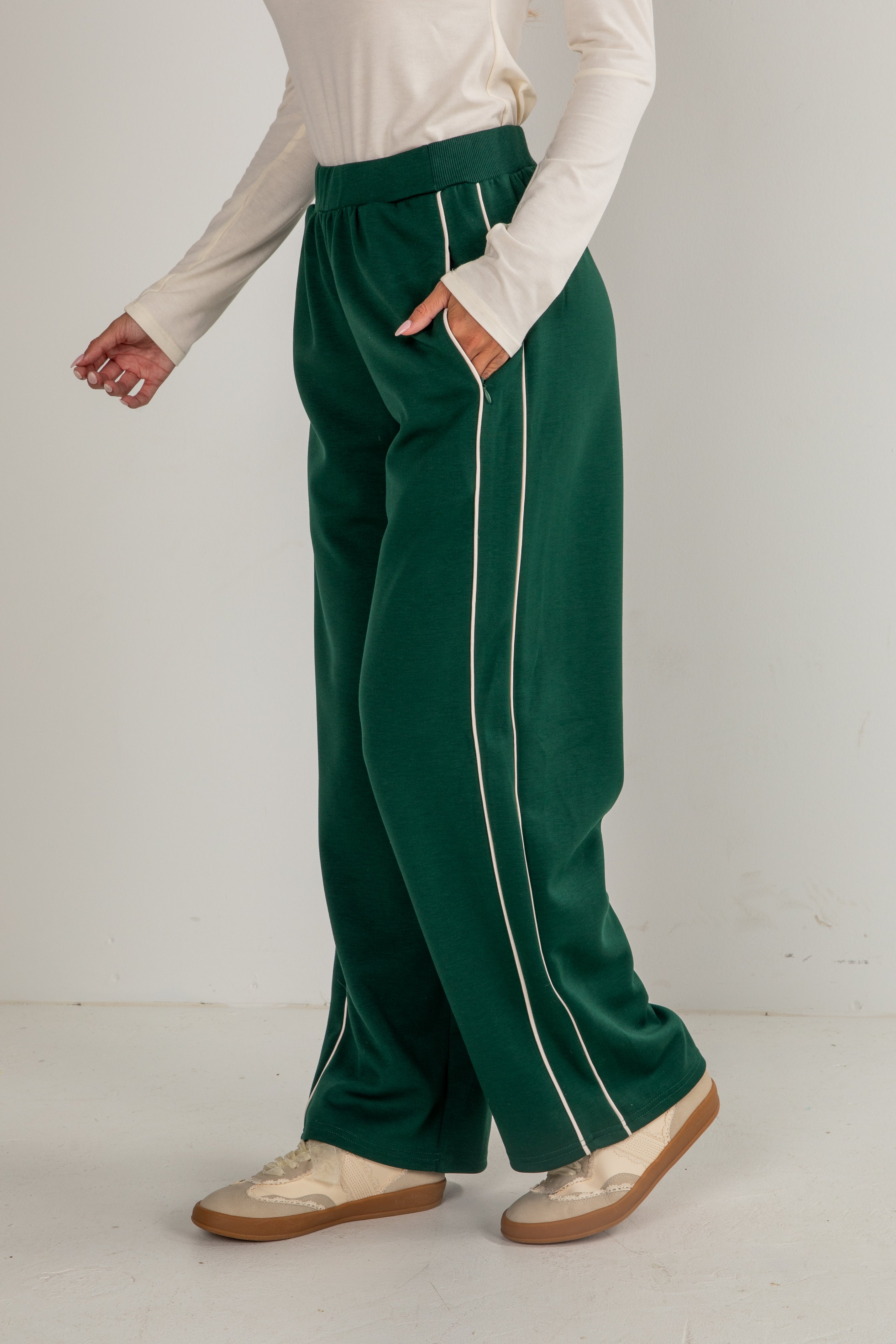 Person wearing green pants with white stripes on a plain background