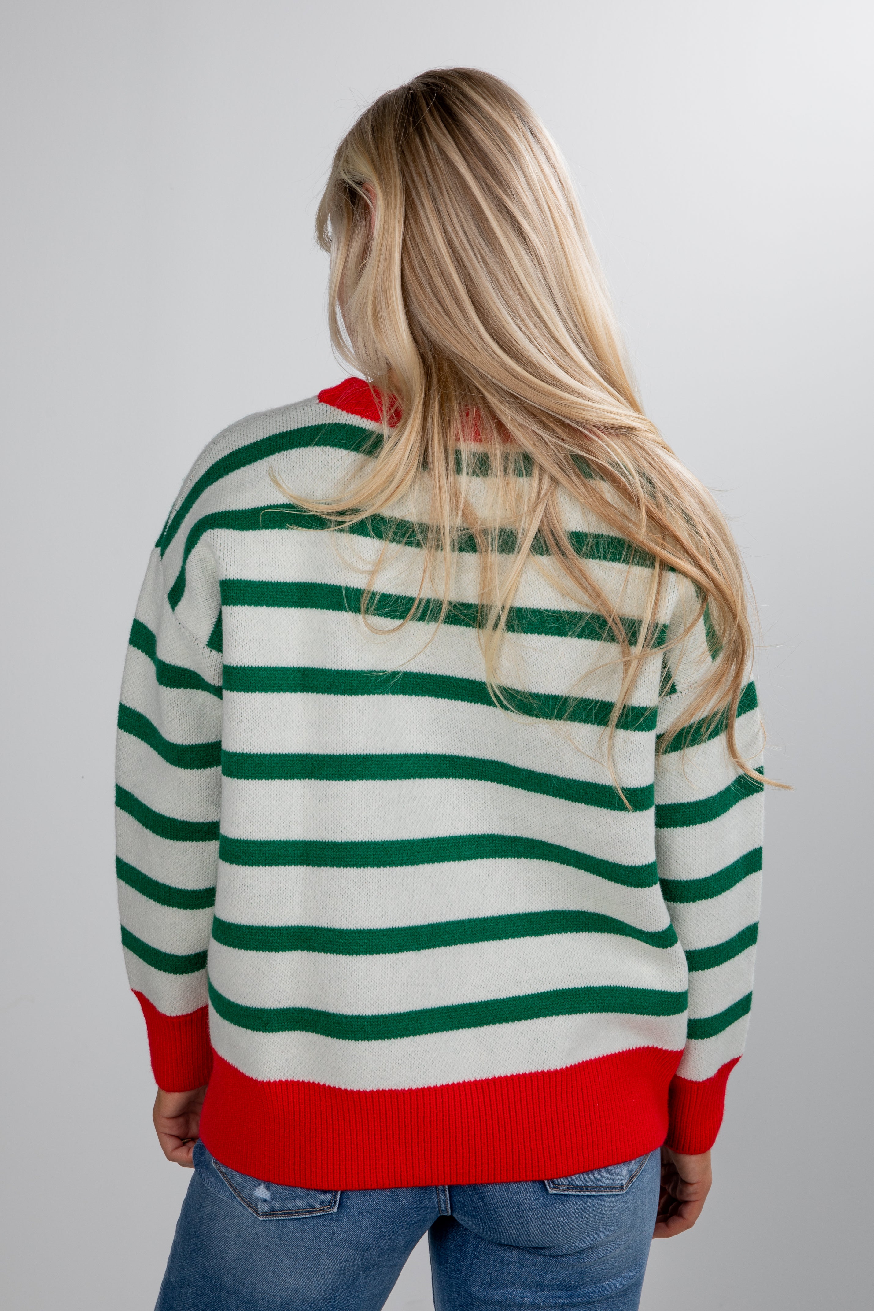 Person wearing a green and red striped sweater on a plain background
