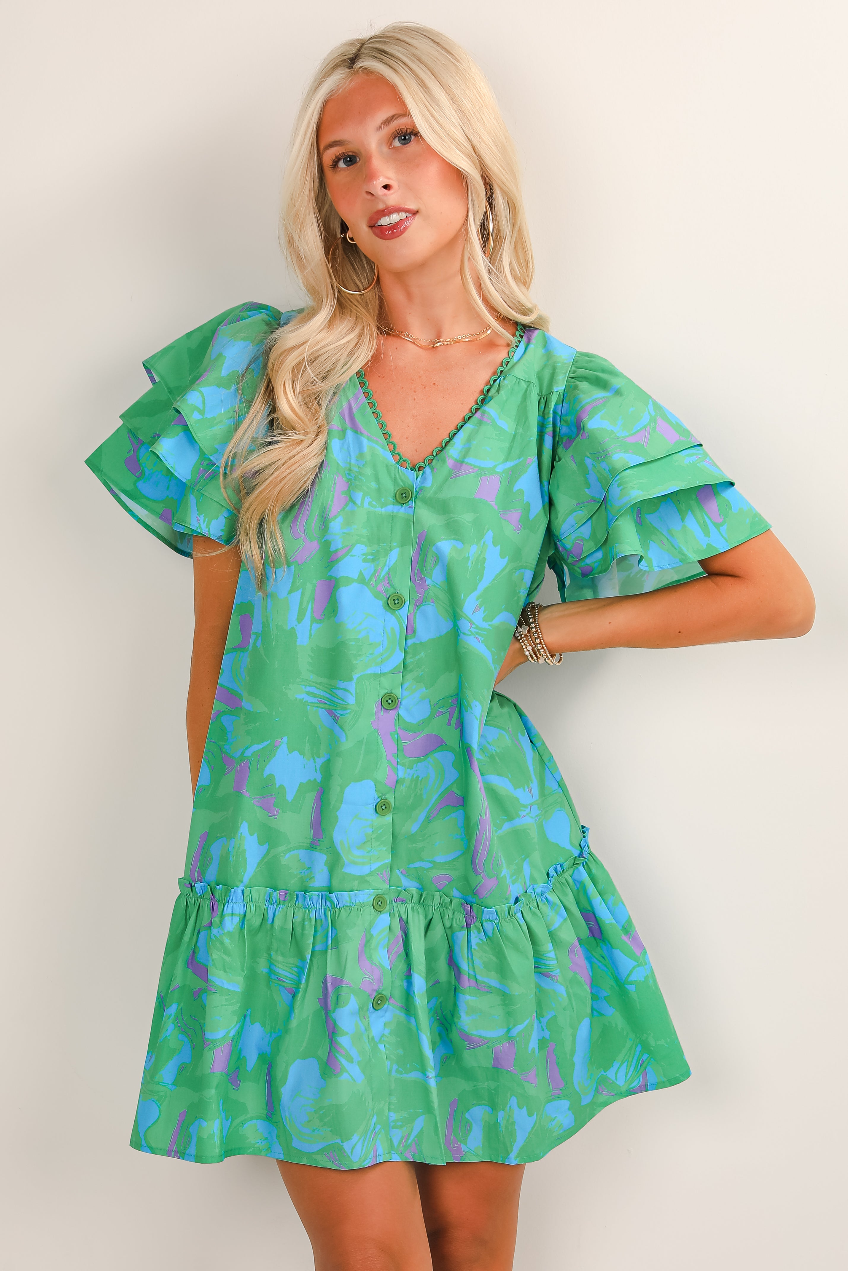 Woman wearing a green dress with blue and purple abstract pattern against a white background