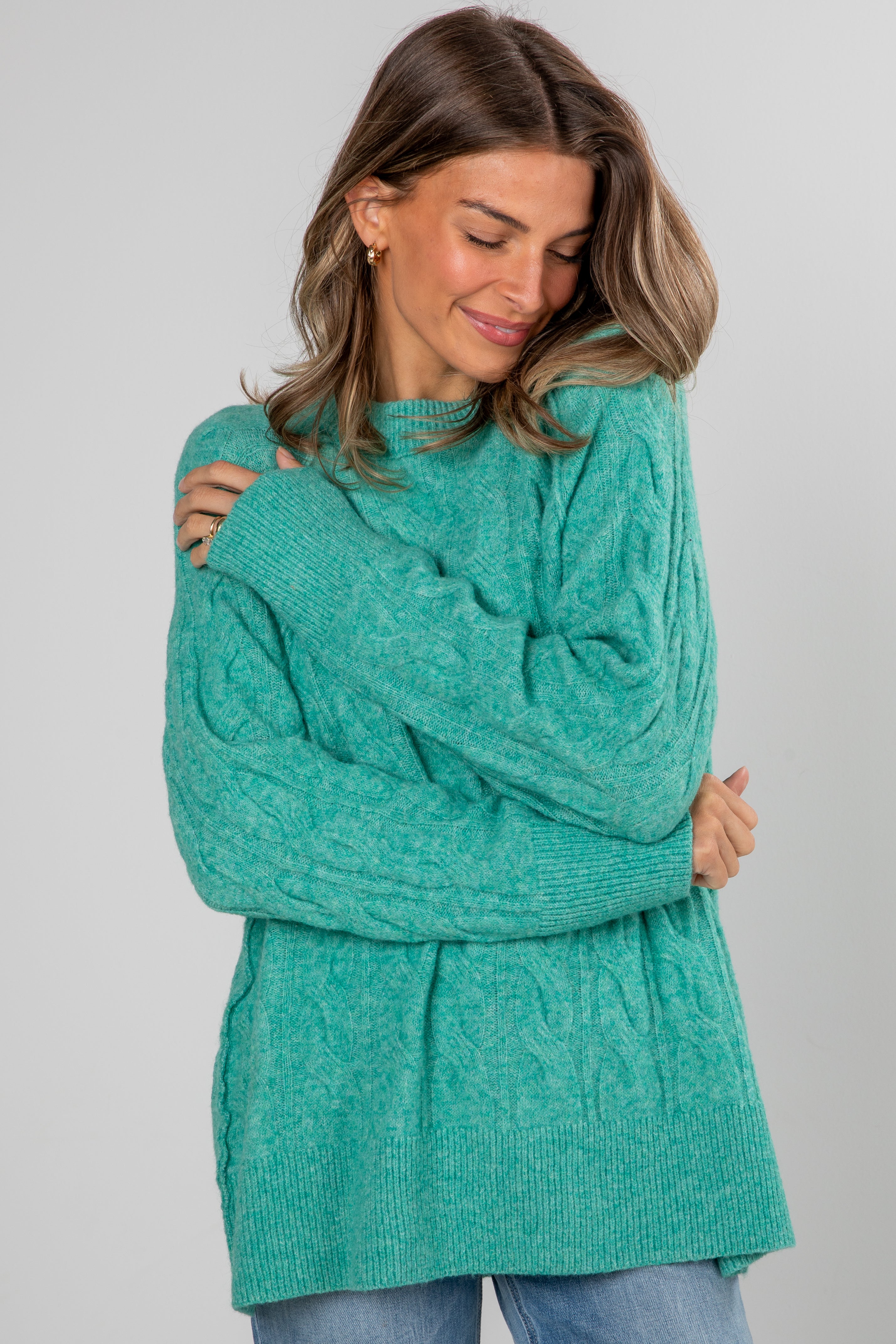 Woman wearing a teal sweater against a plain background