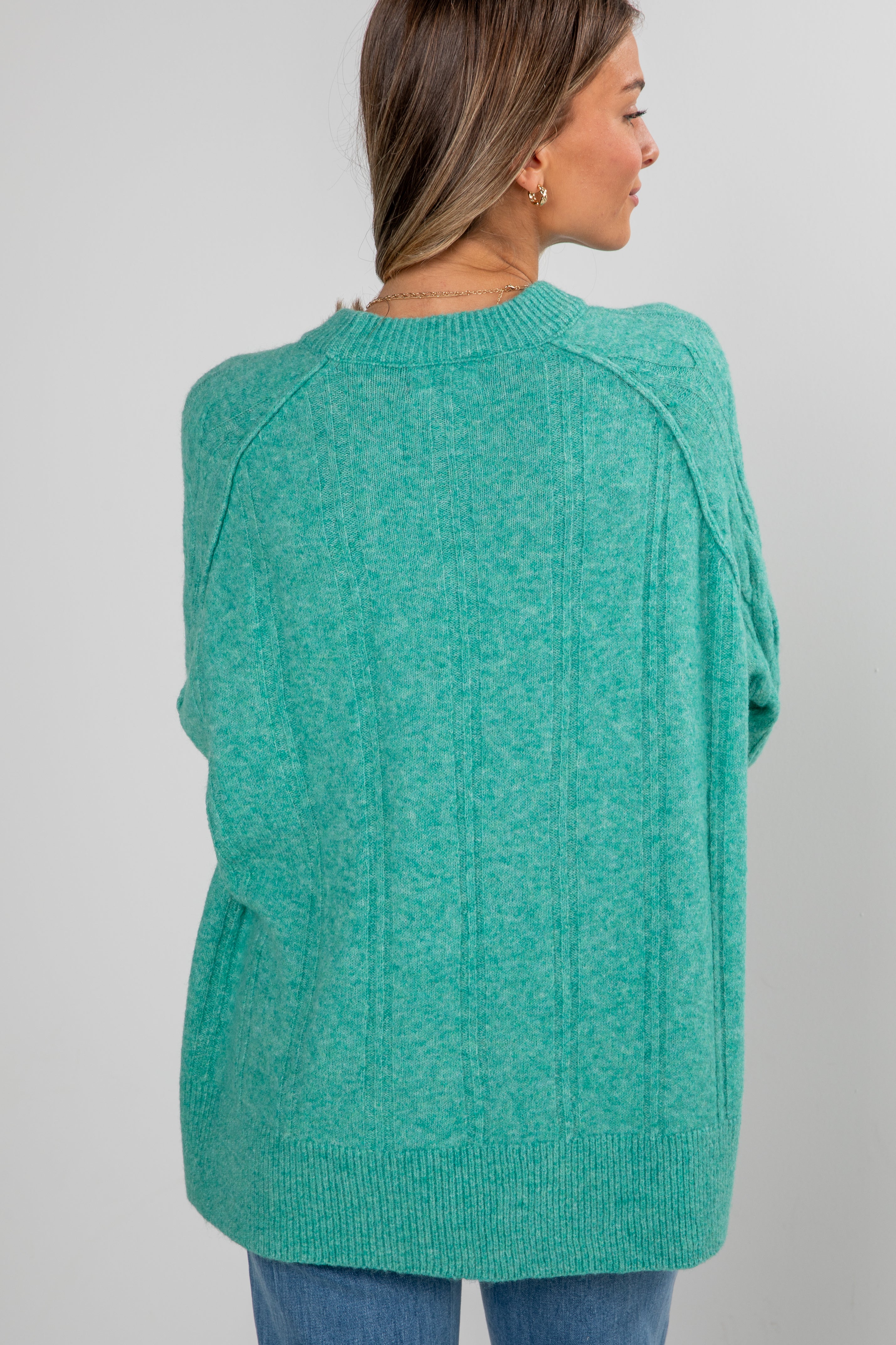 Person wearing a teal sweater on a plain background