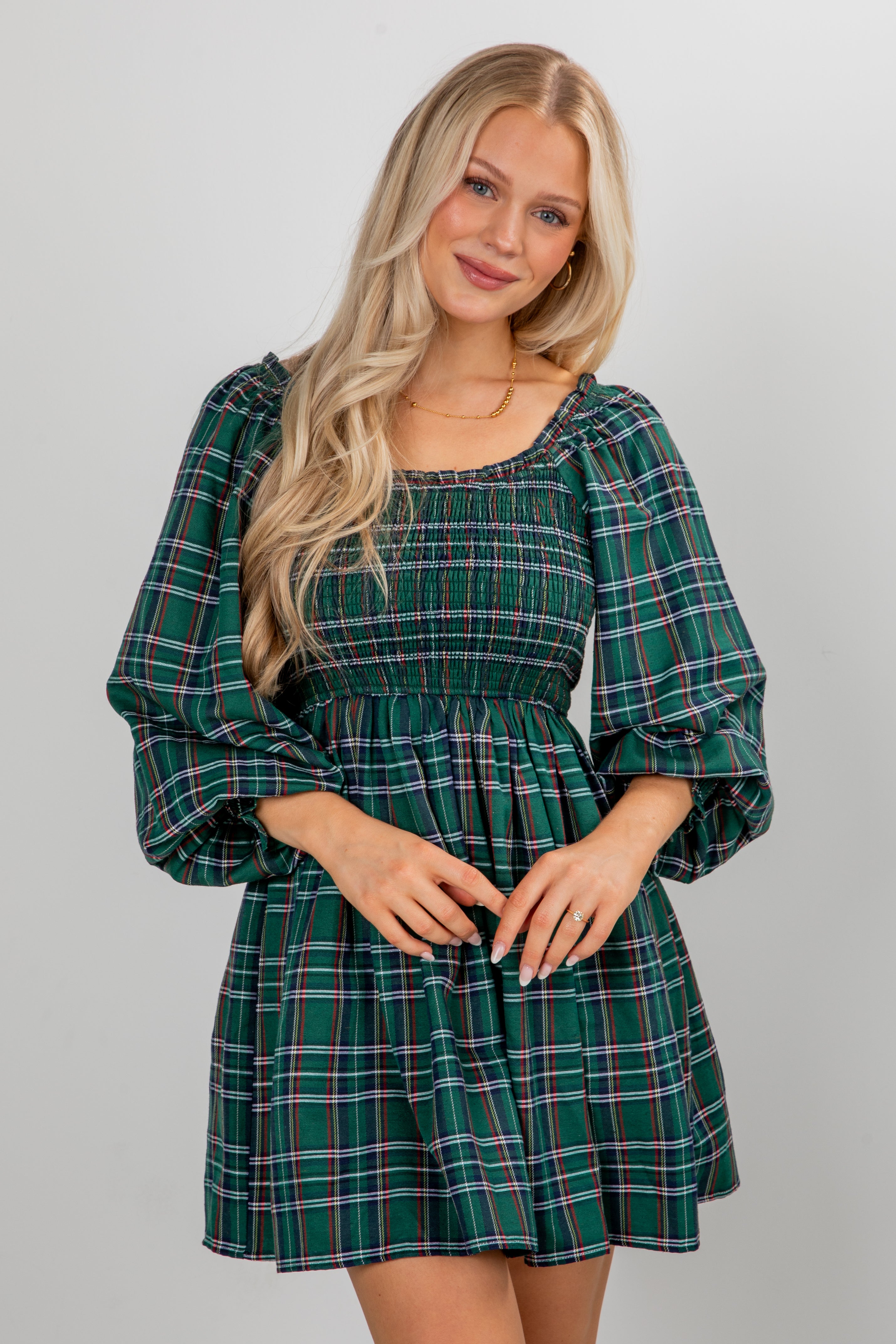 Woman wearing a green plaid dress against a plain background