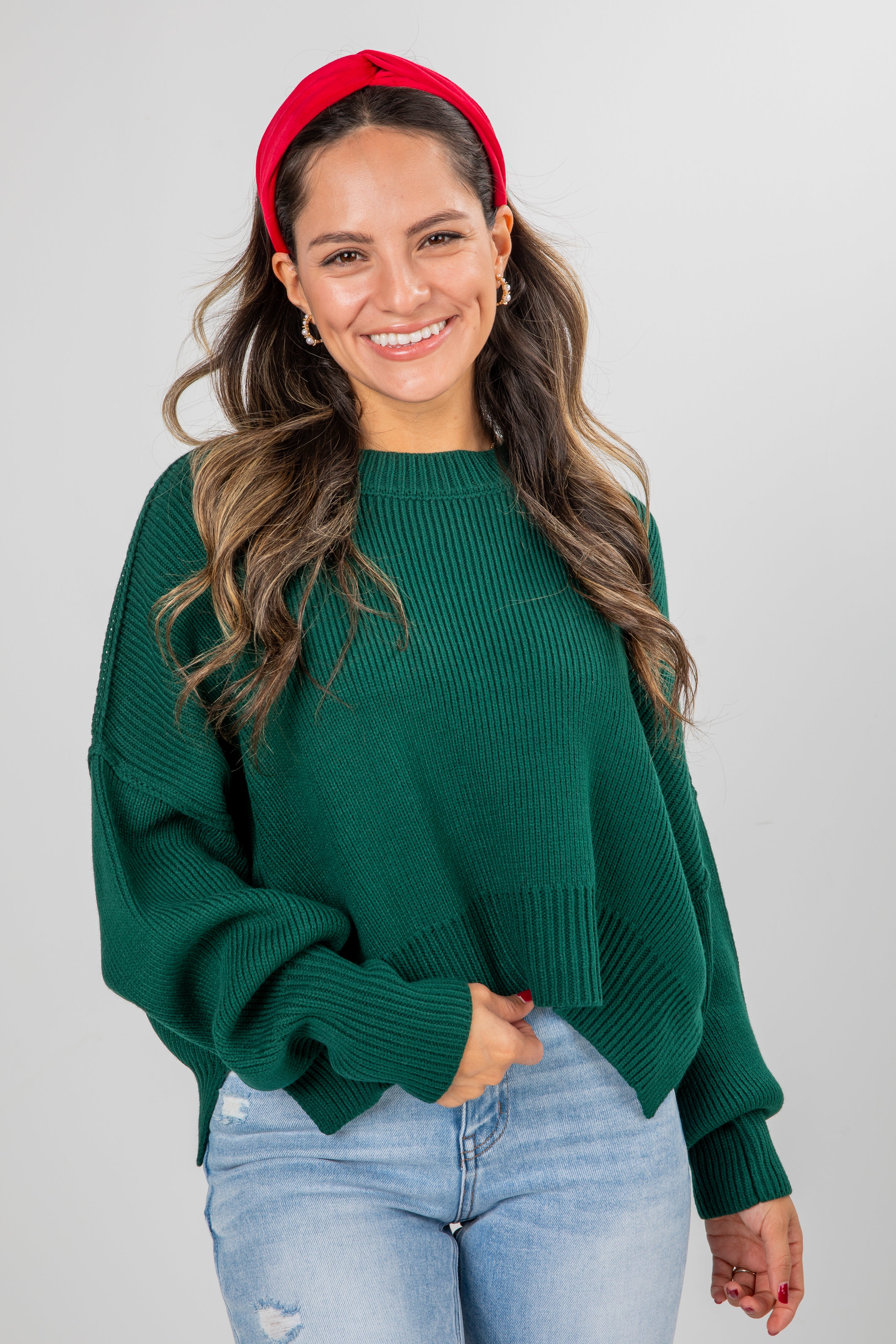 Woman wearing a green sweater and red headband against a gray background