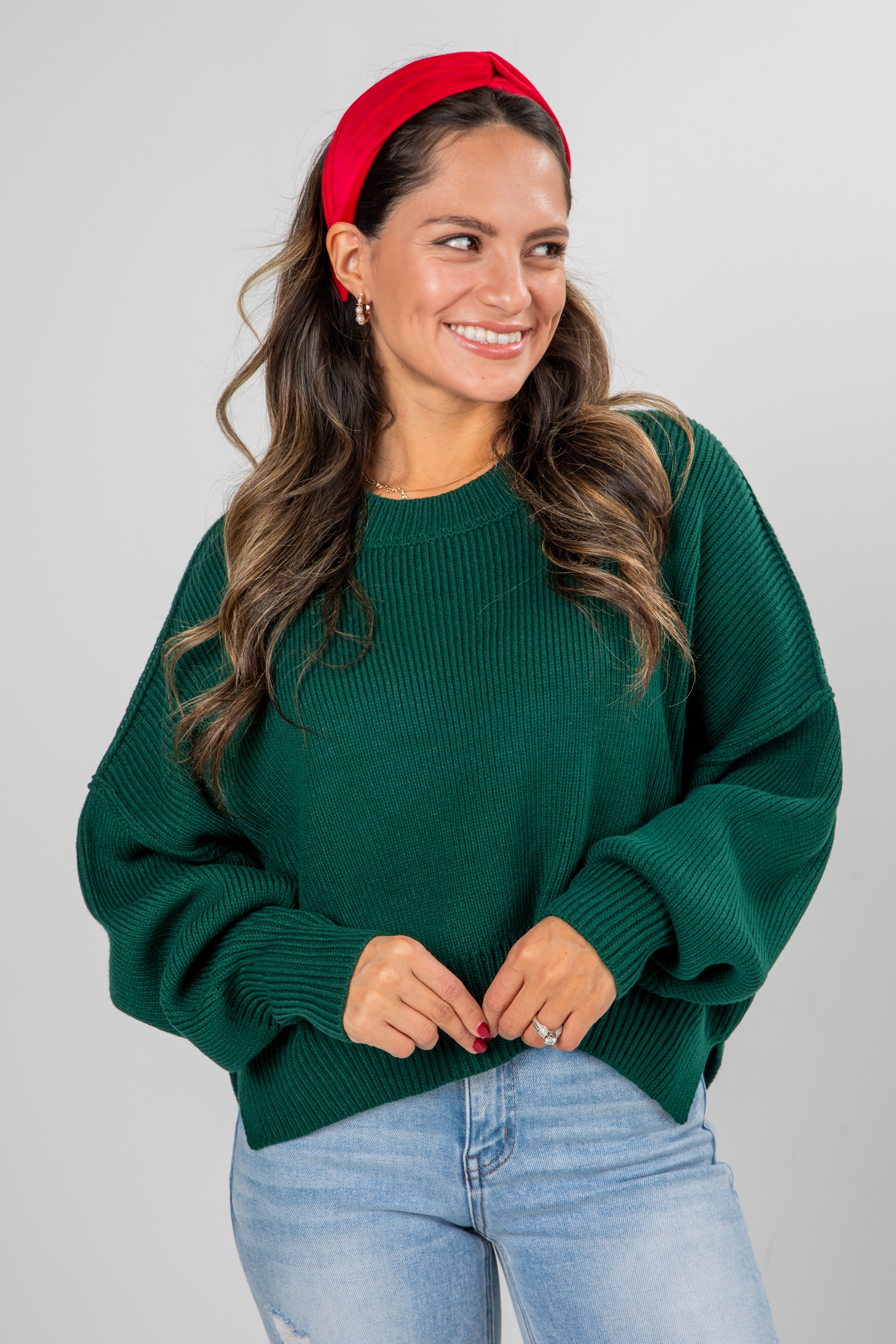 Woman wearing a green sweater and red headband on a plain background