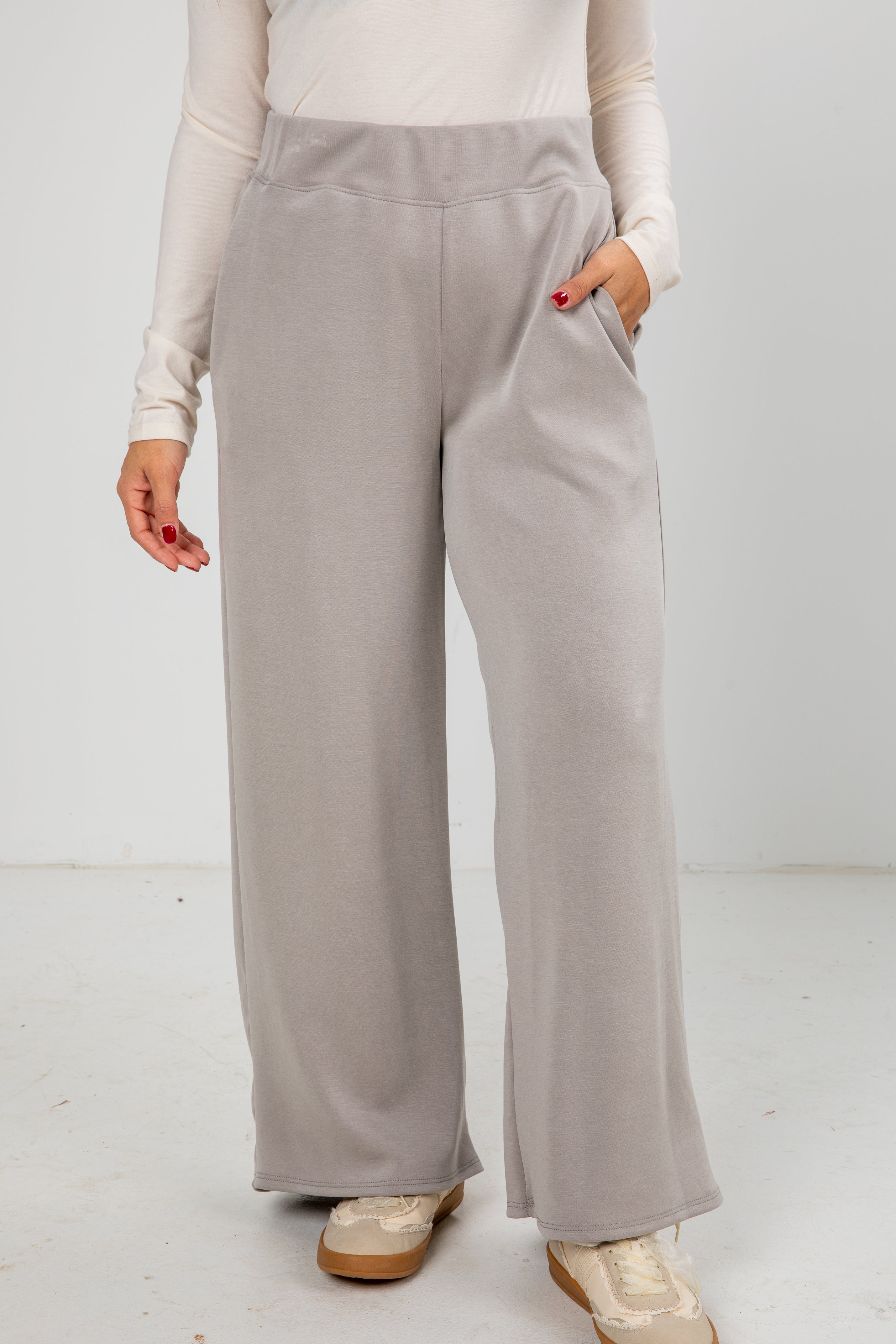 Person wearing light gray wide-leg pants on a white background