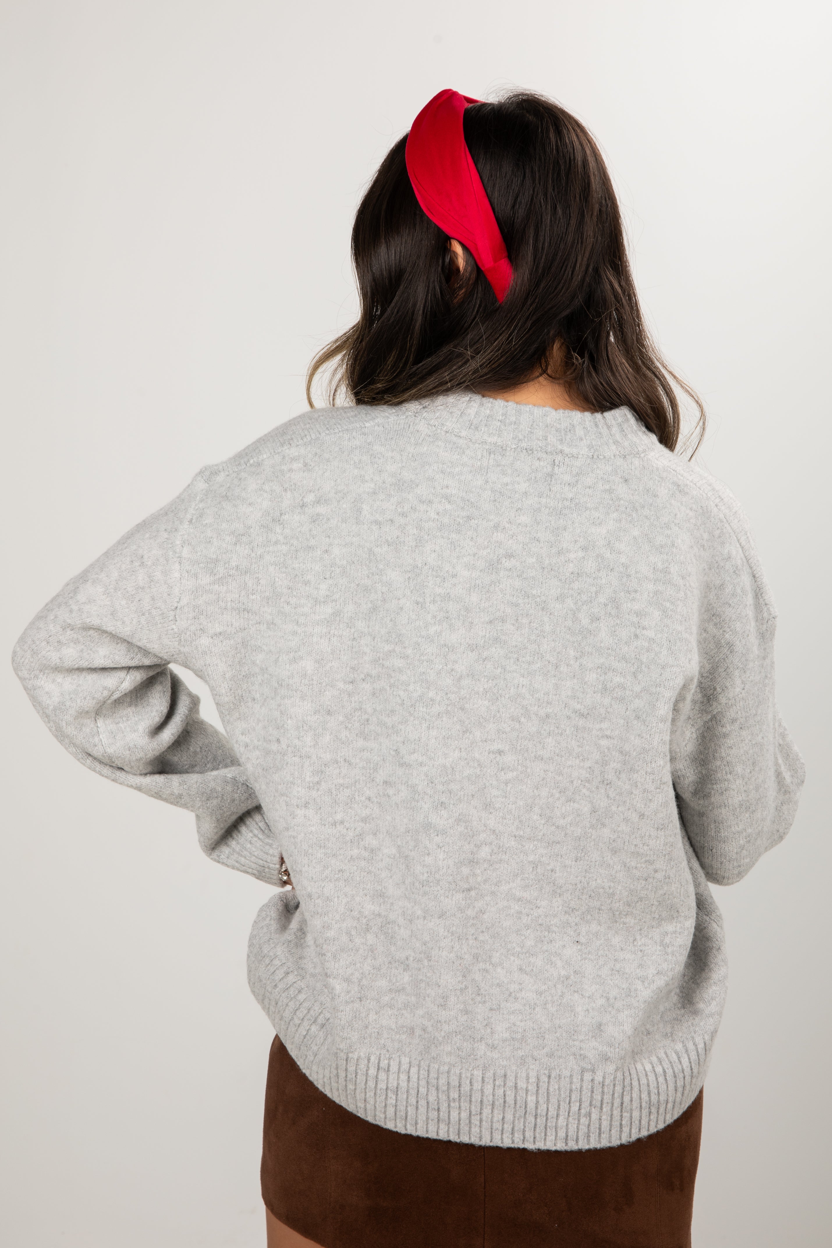 Person wearing a gray sweater and brown pants with a red headband on a white background