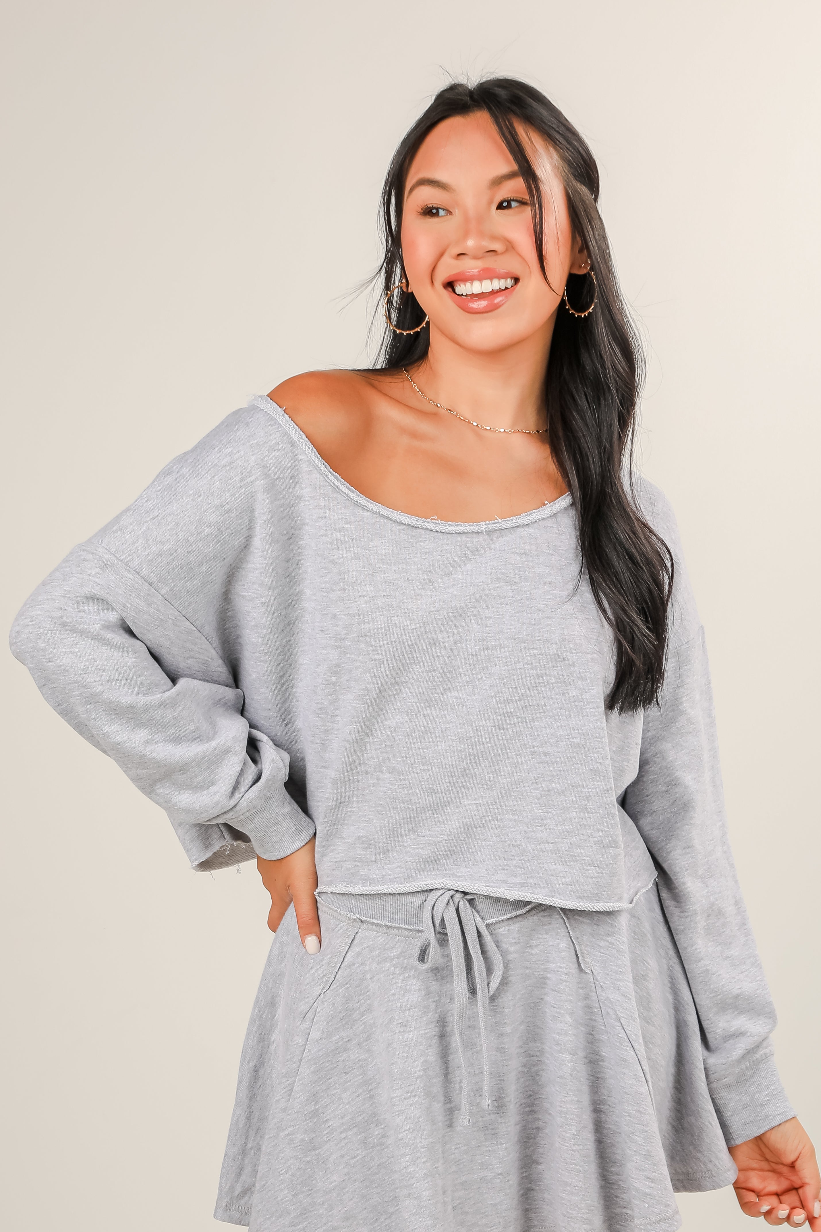 Woman wearing a gray off-shoulder top and skirt set against a plain background