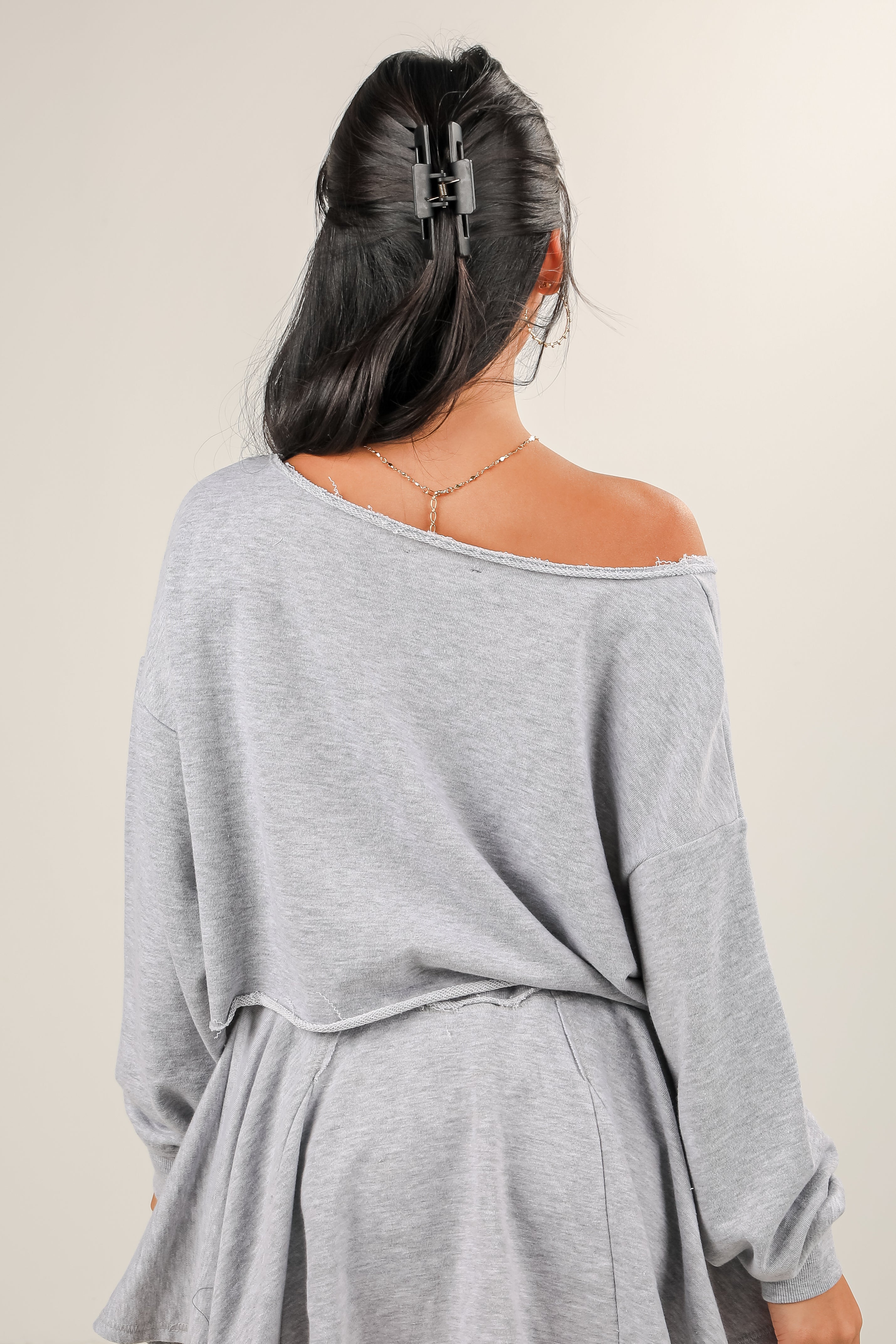 Woman wearing a gray off-shoulder top with a plain background