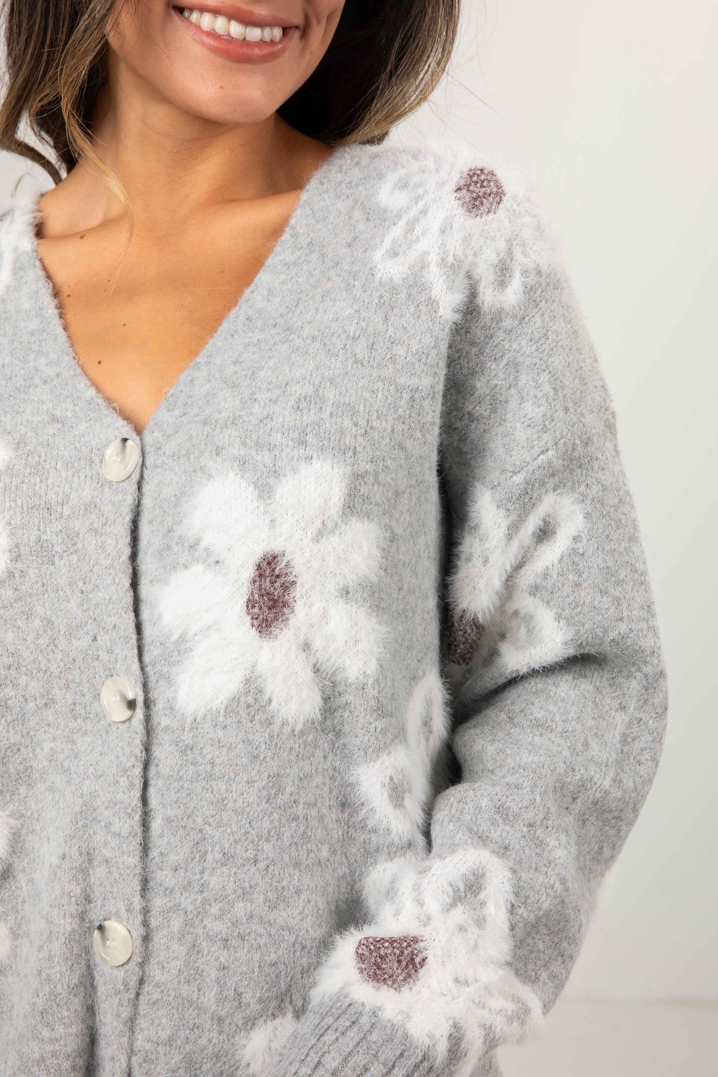 Woman wearing a gray cardigan with floral patterns on a white background