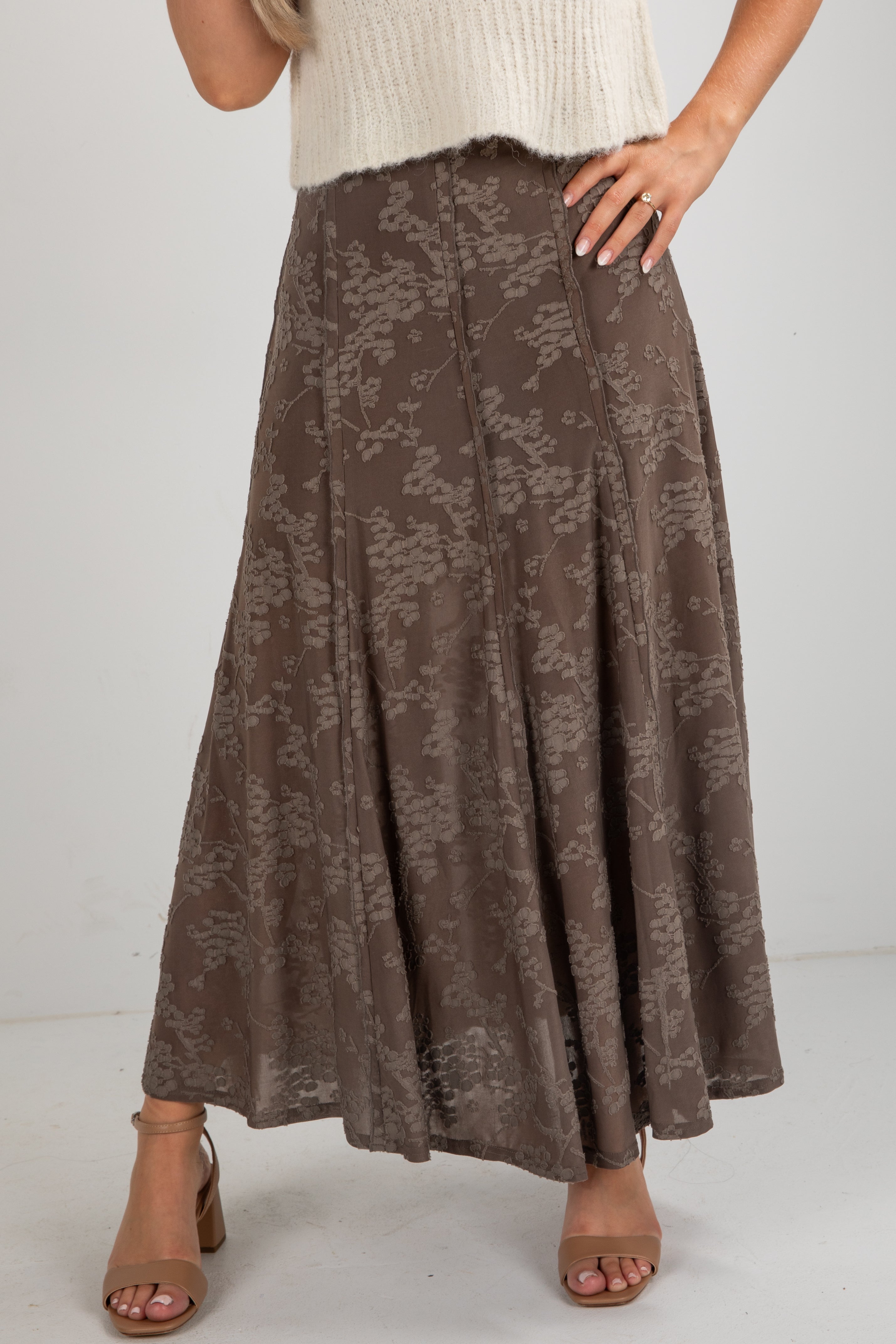 Brown floral patterned skirt worn by a person on a white background