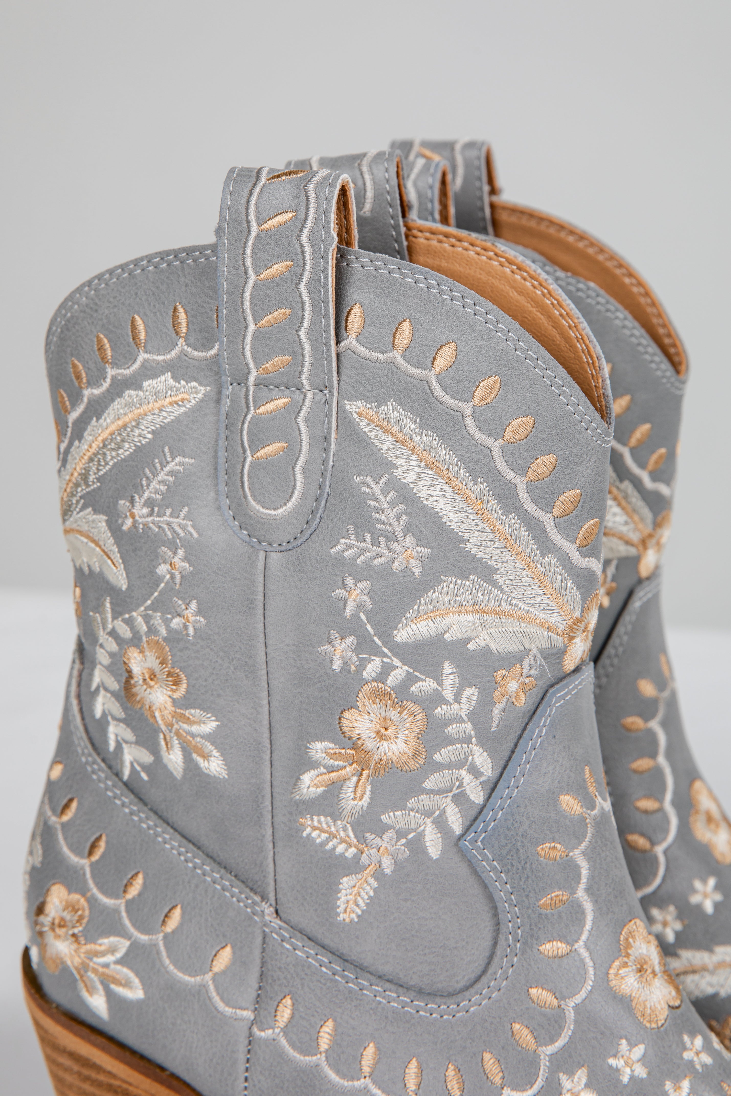 Gray cowboy boots with floral embroidery on a light gray background