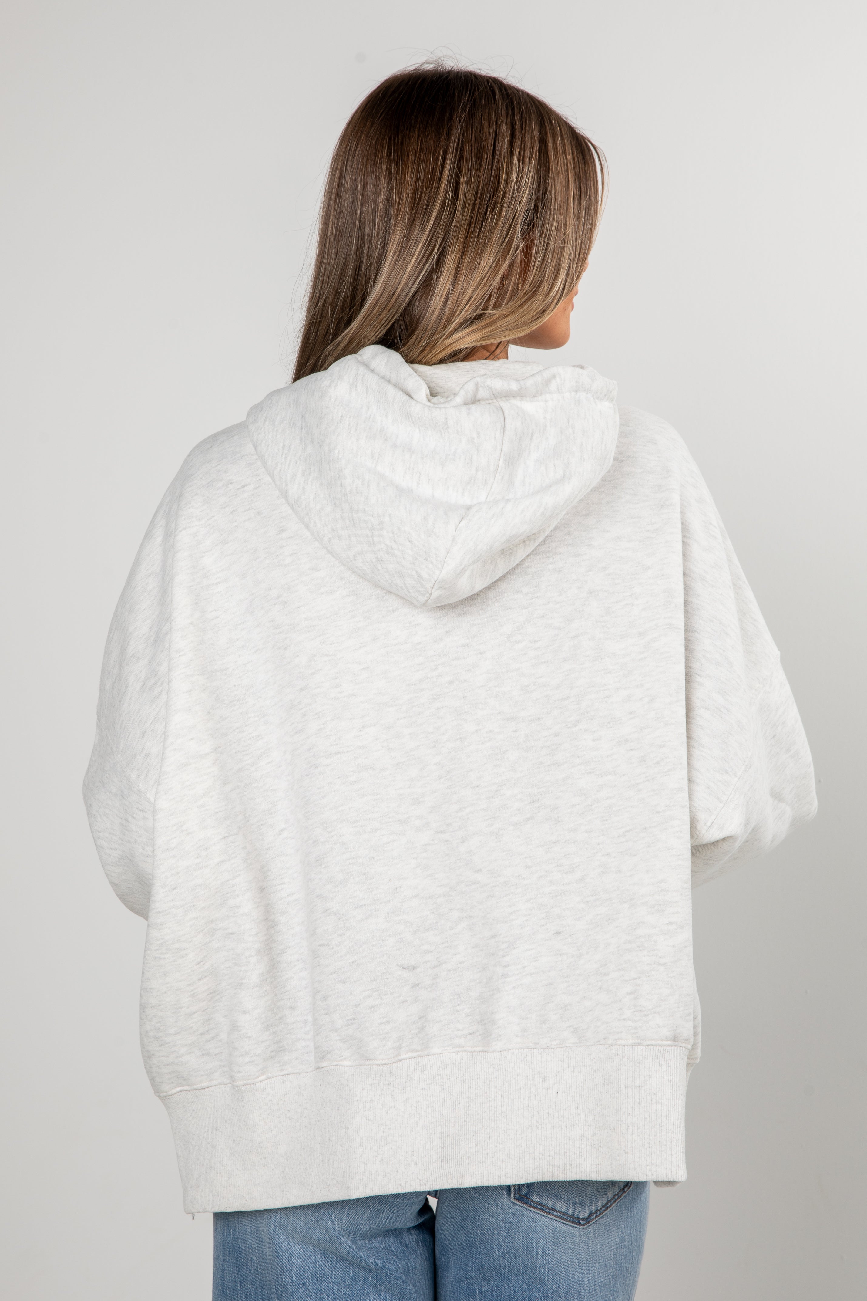 Person wearing a light gray hoodie from behind on a plain background