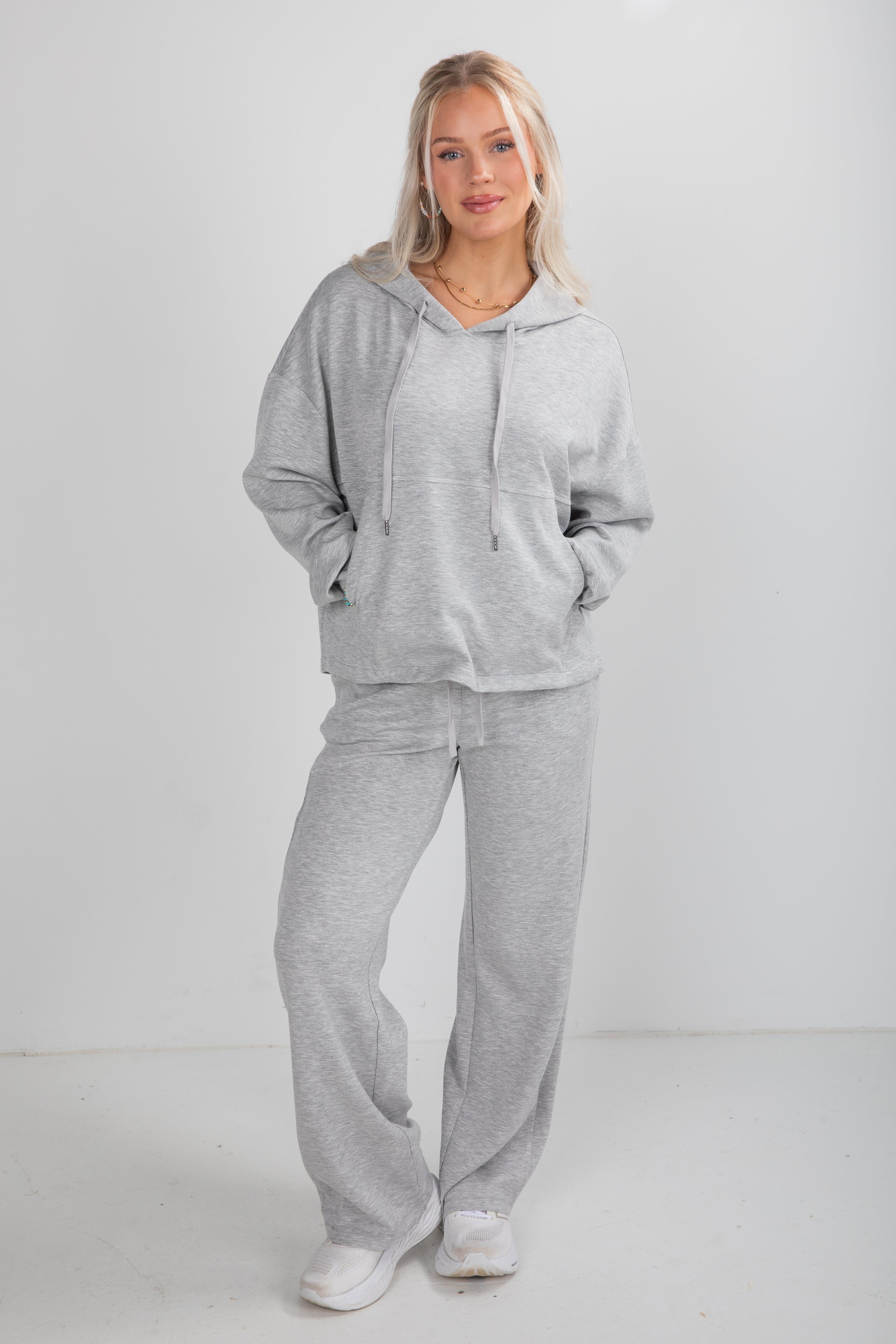Woman wearing a gray tracksuit against a white background