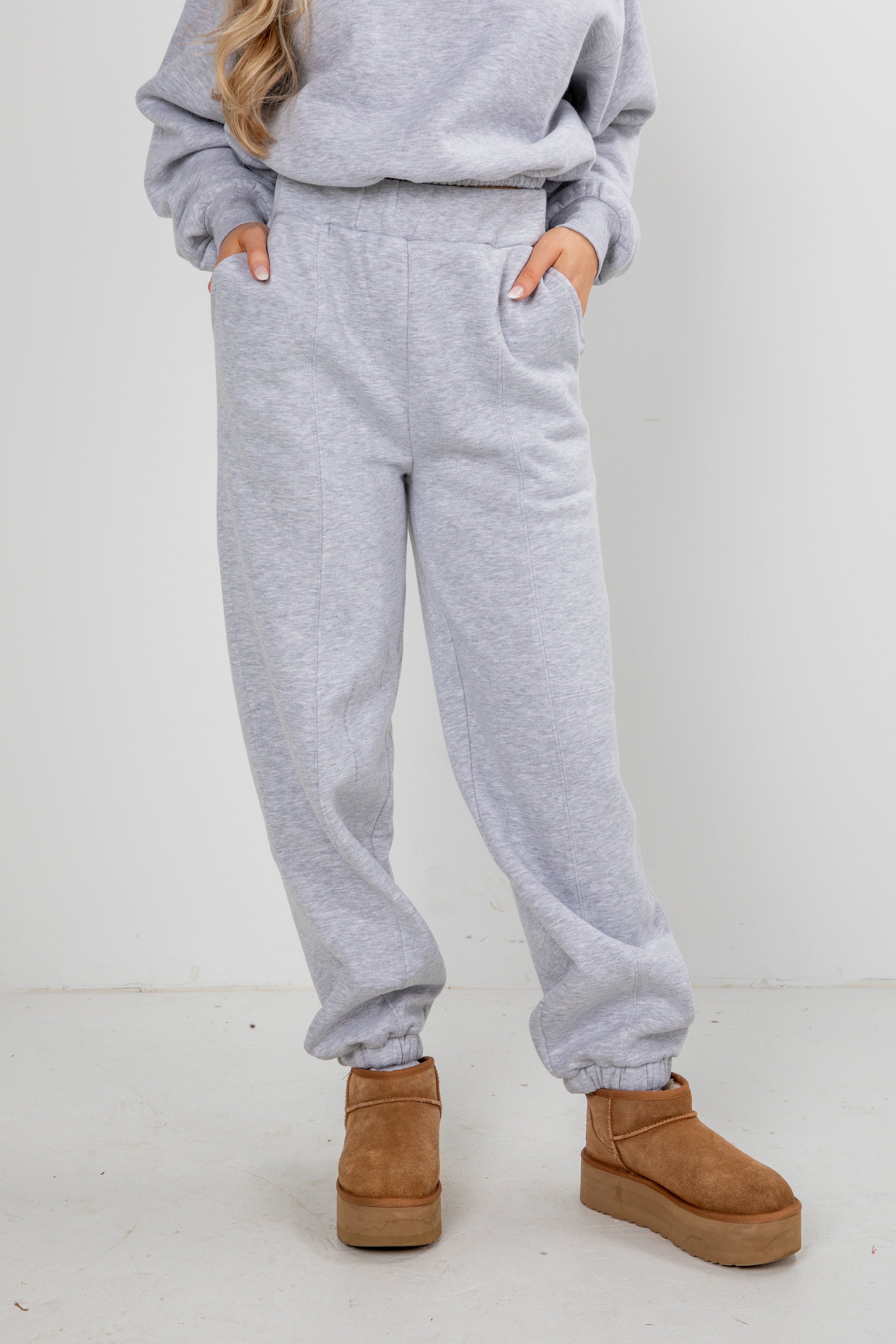Person wearing gray sweatpants and brown boots on a white background