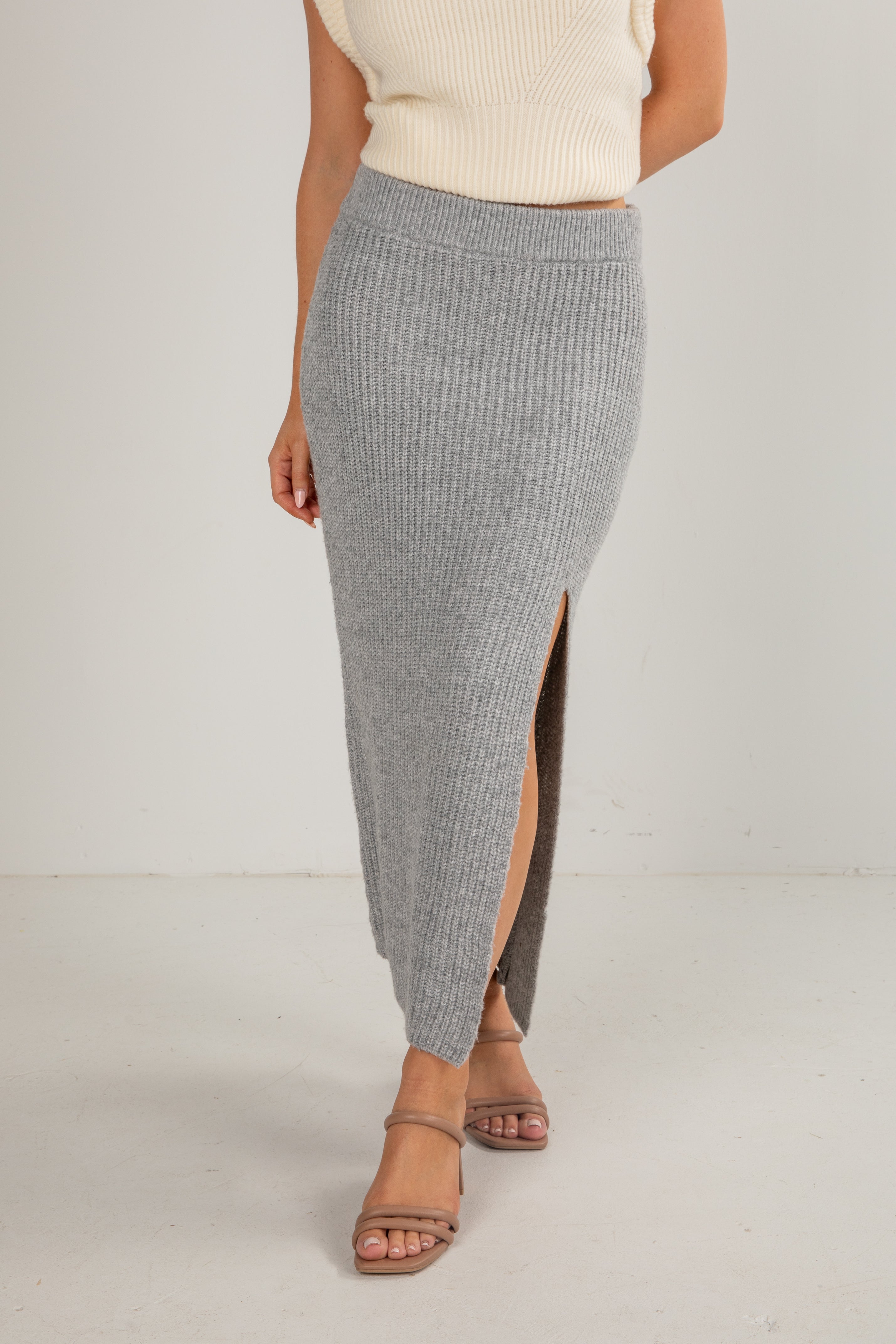 Person wearing a gray ribbed skirt with a white background