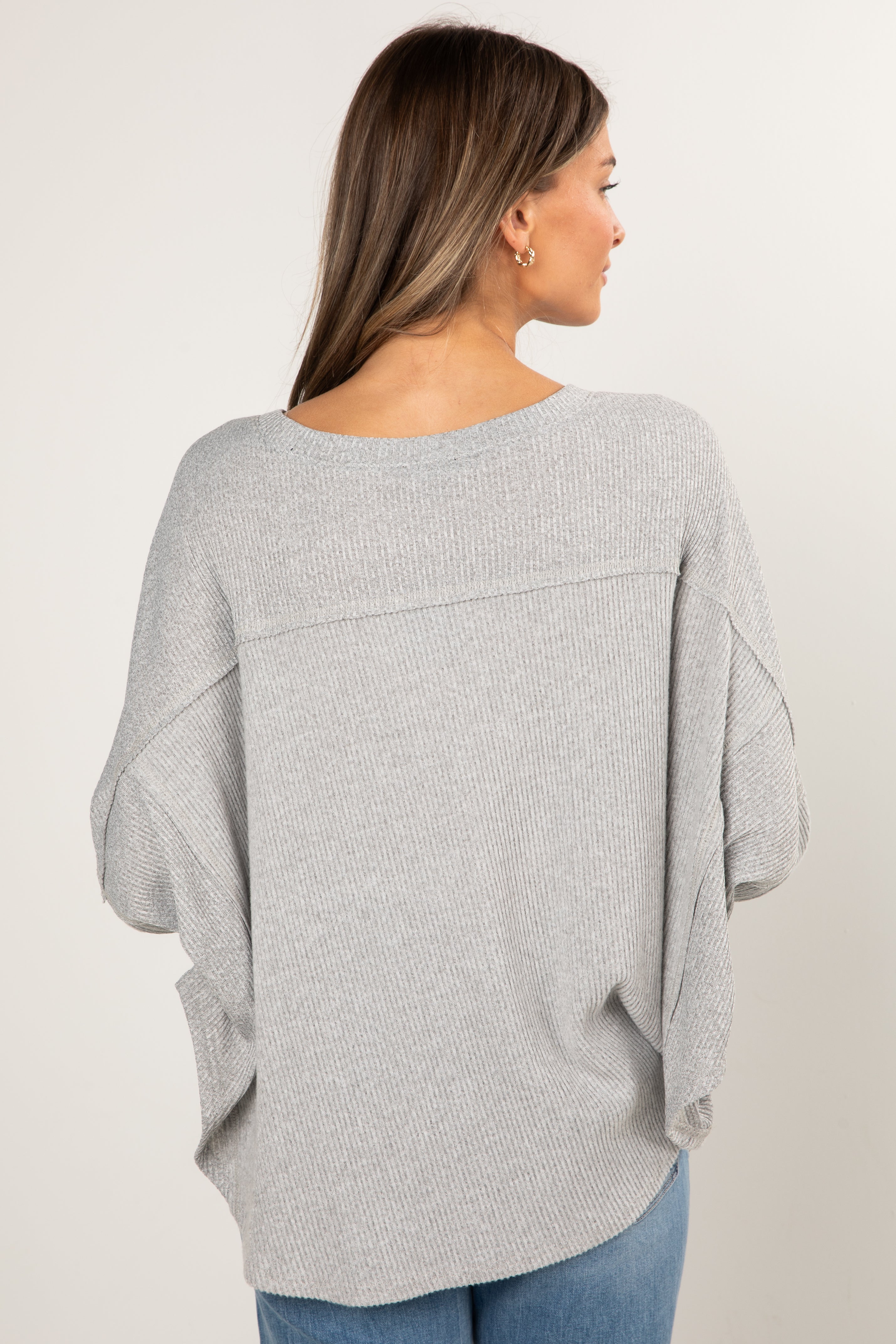 Woman wearing a gray sweater with a plain background