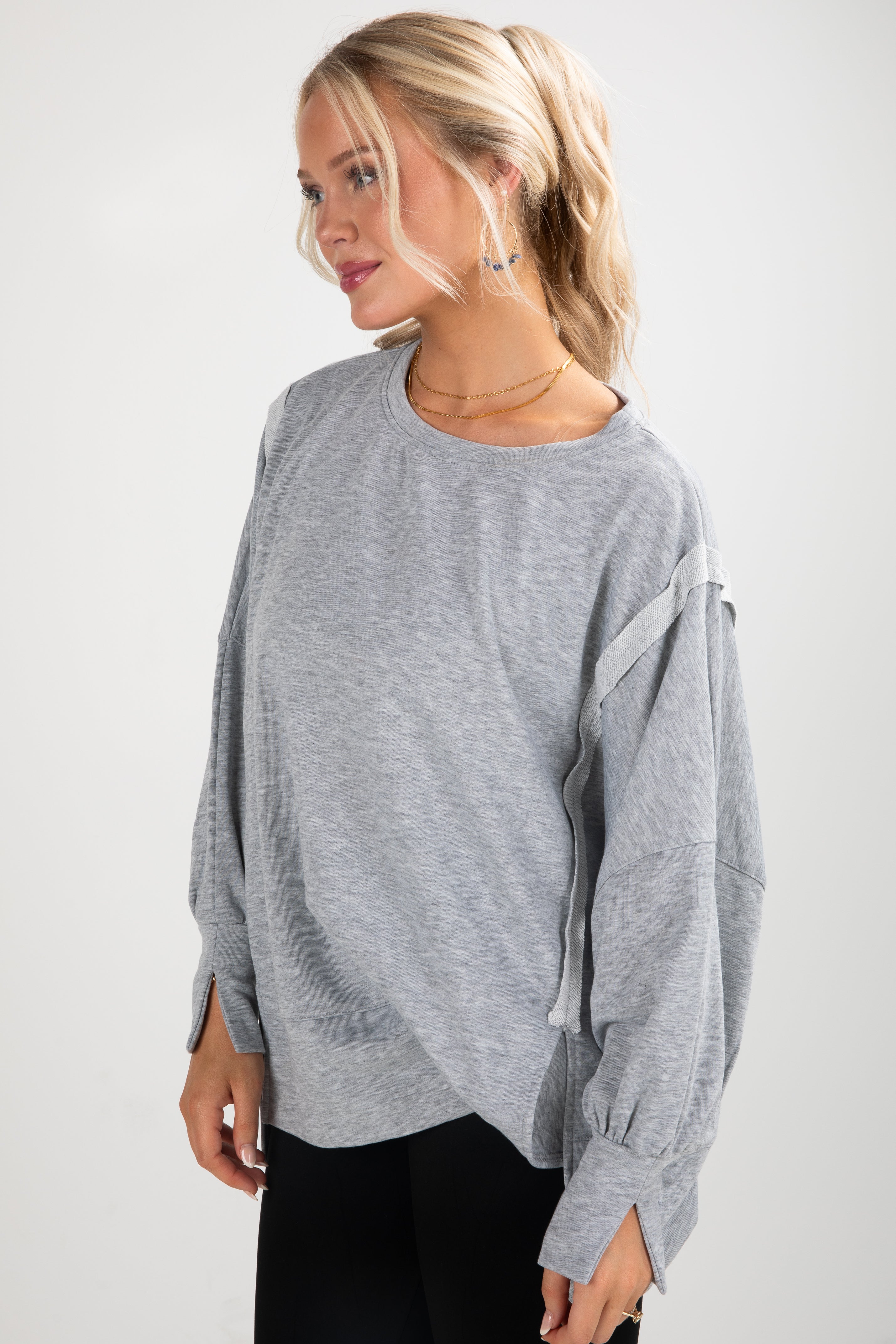 Woman wearing a gray oversized sweater against a white background