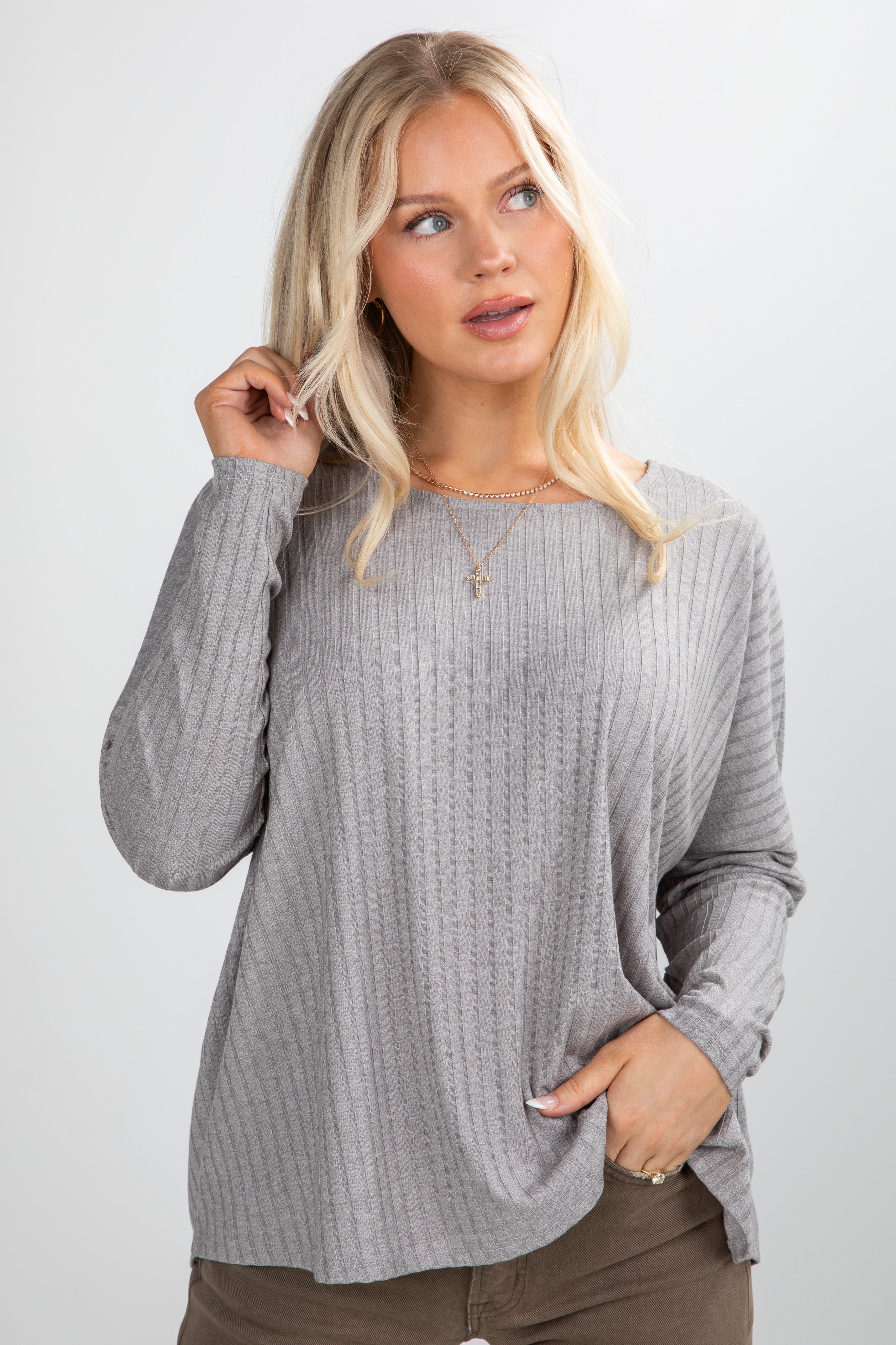 Woman wearing a gray ribbed sweater against a white background