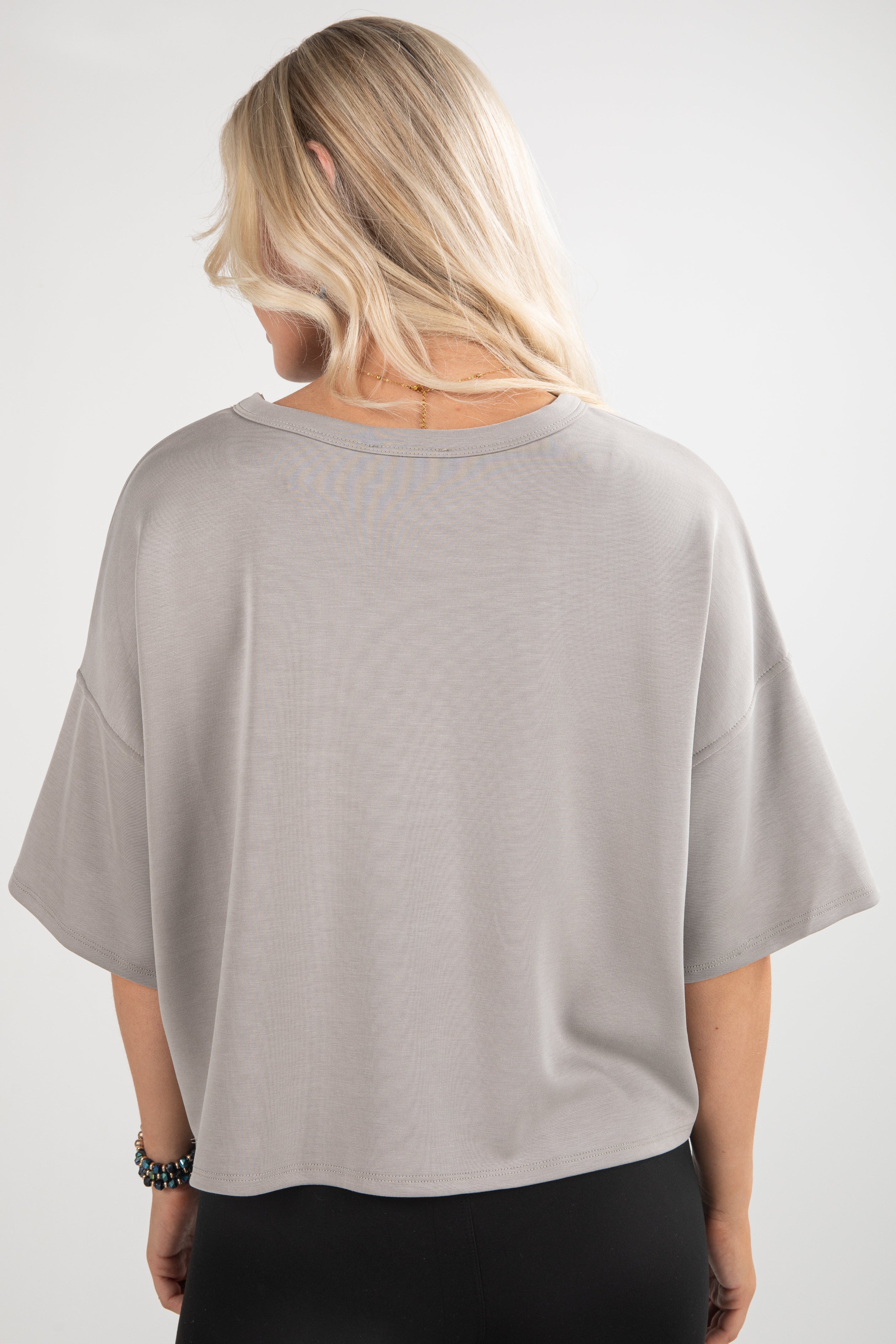 Person wearing a light gray oversized shirt on a white background