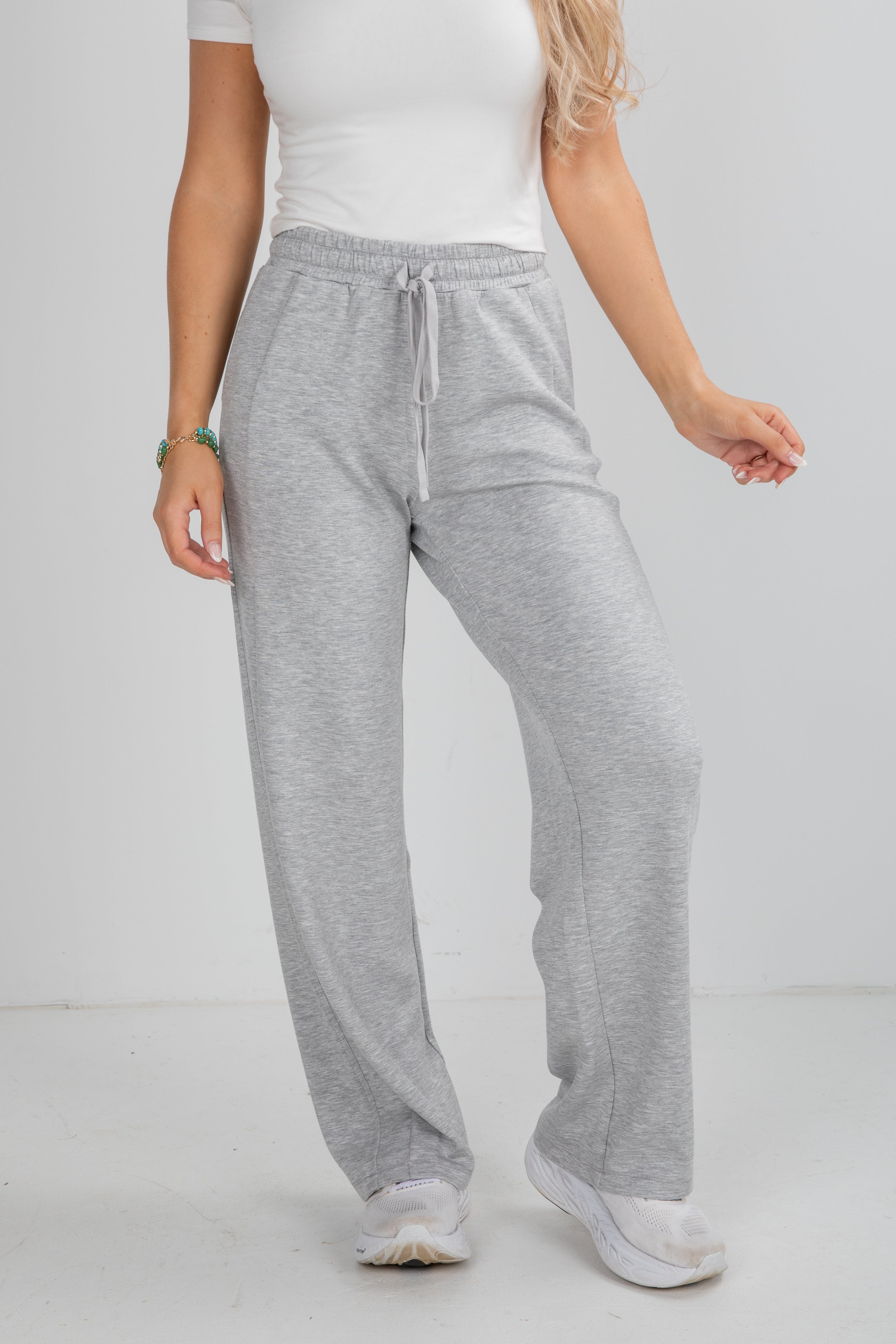 Person wearing gray sweatpants and a white top on a plain background
