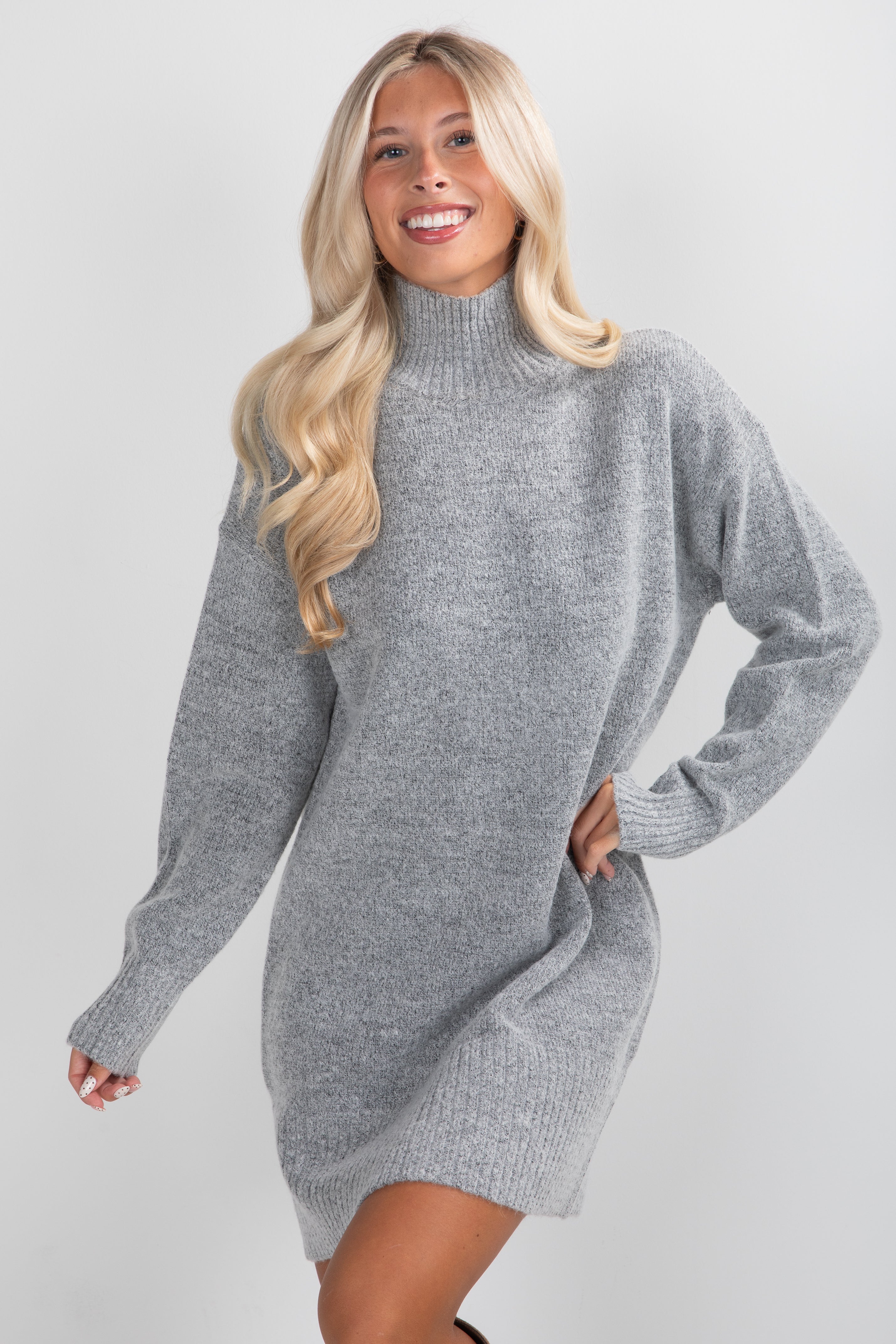 Woman wearing a gray sweater dress against a plain background