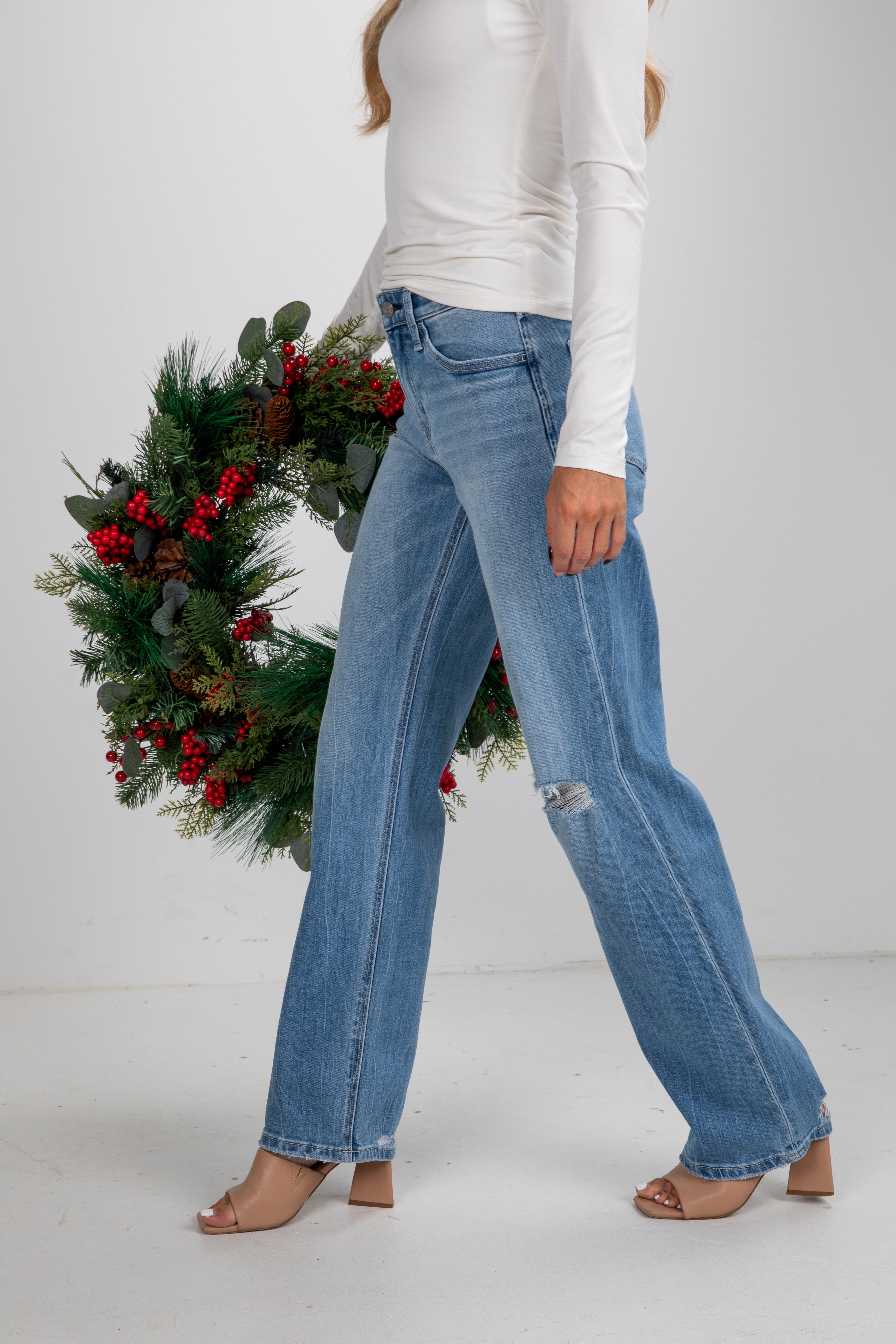 Person wearing blue jeans with a Christmas wreath in the background