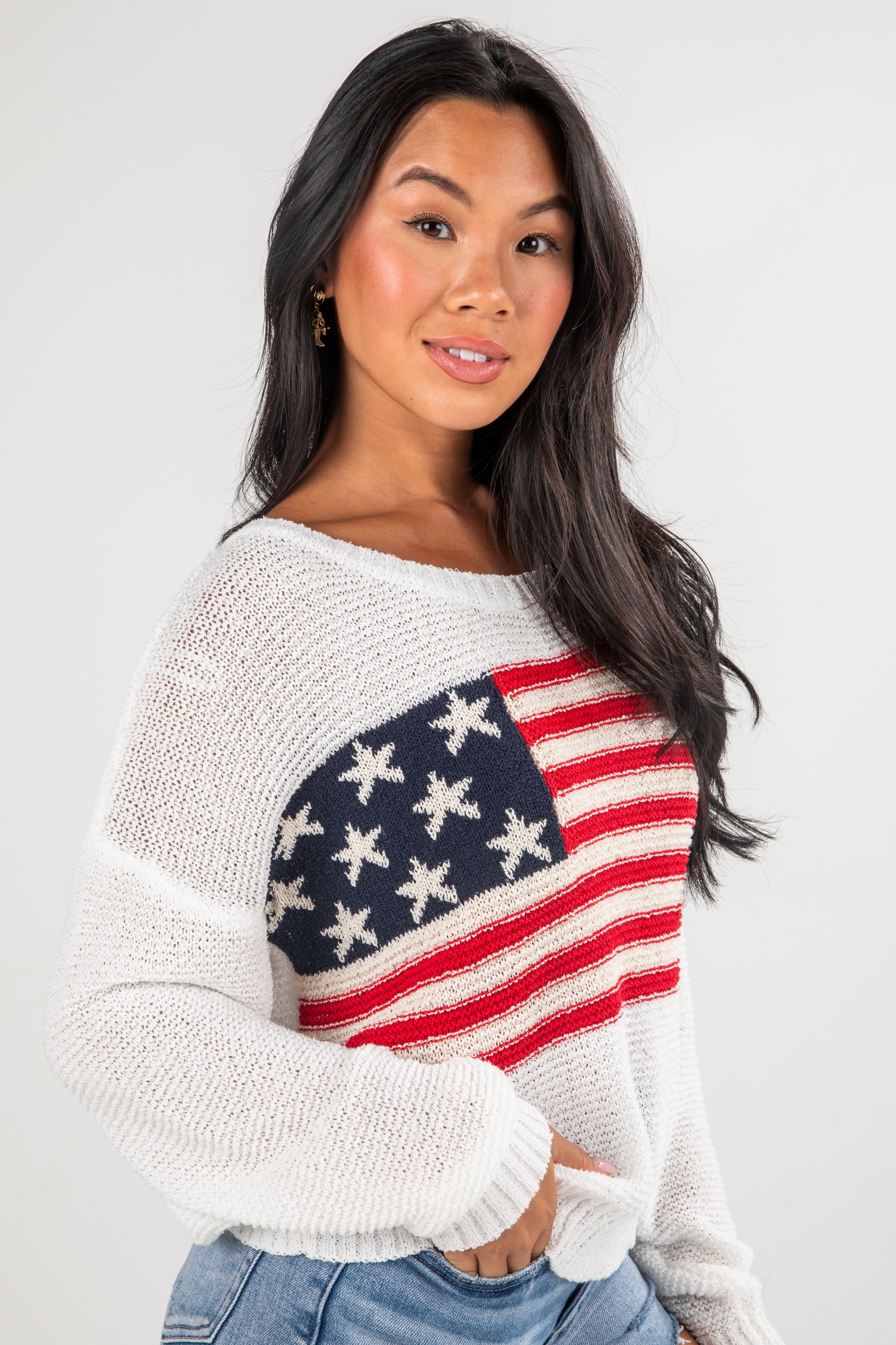 Woman wearing a sweater with an American flag design on a plain background