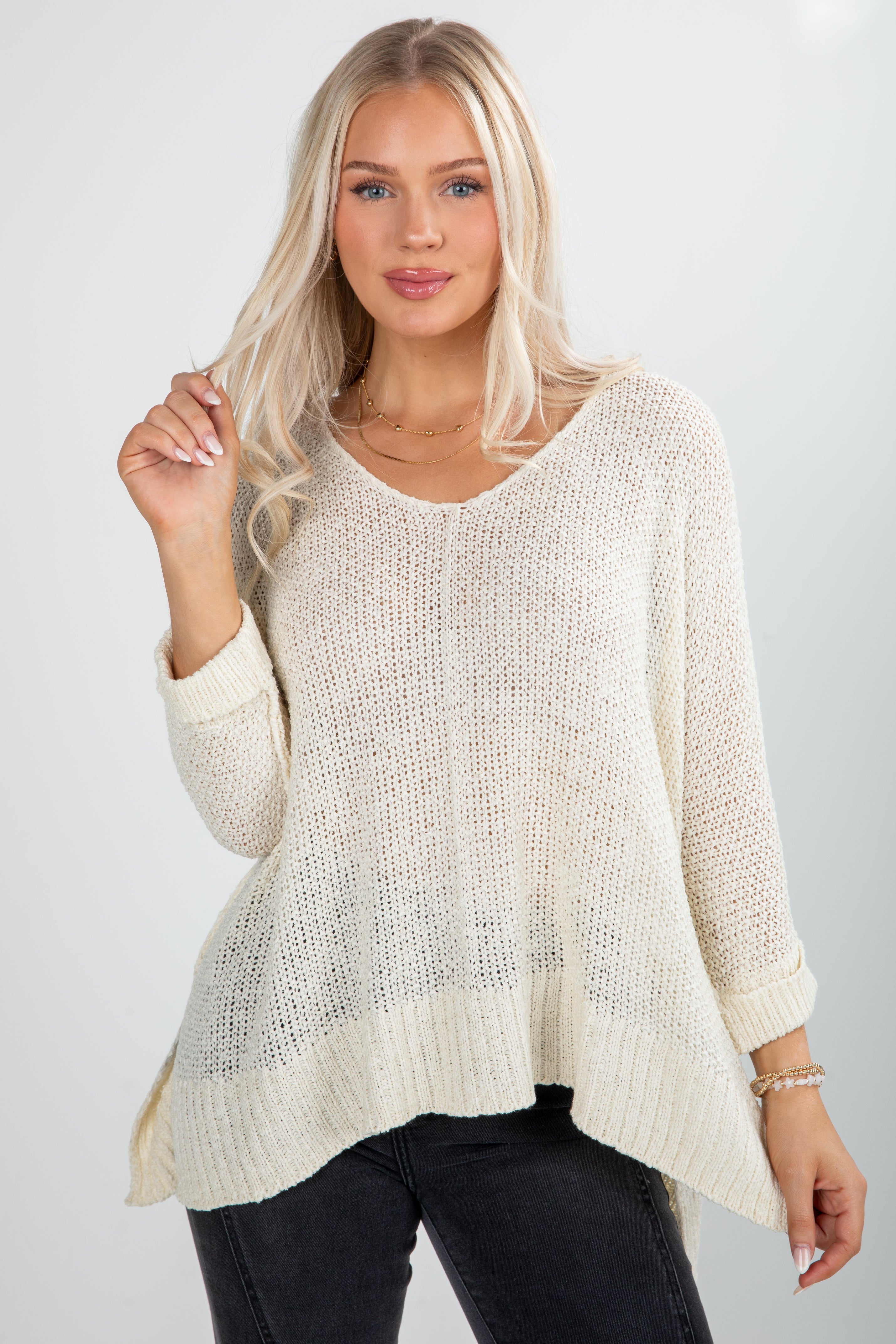 Woman wearing a cream knit sweater against a plain background
