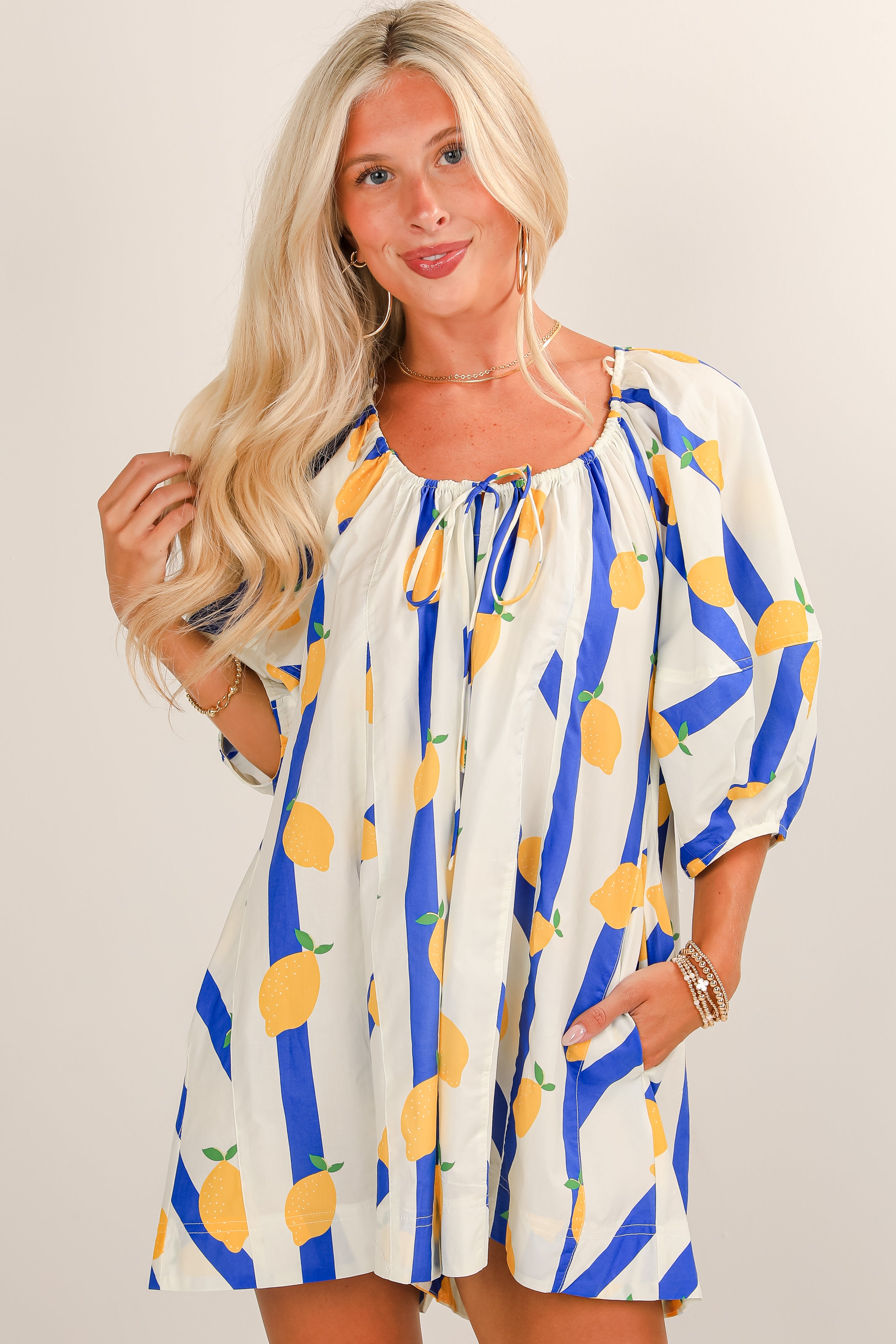 Woman wearing a colorful dress with lemon pattern on a plain background