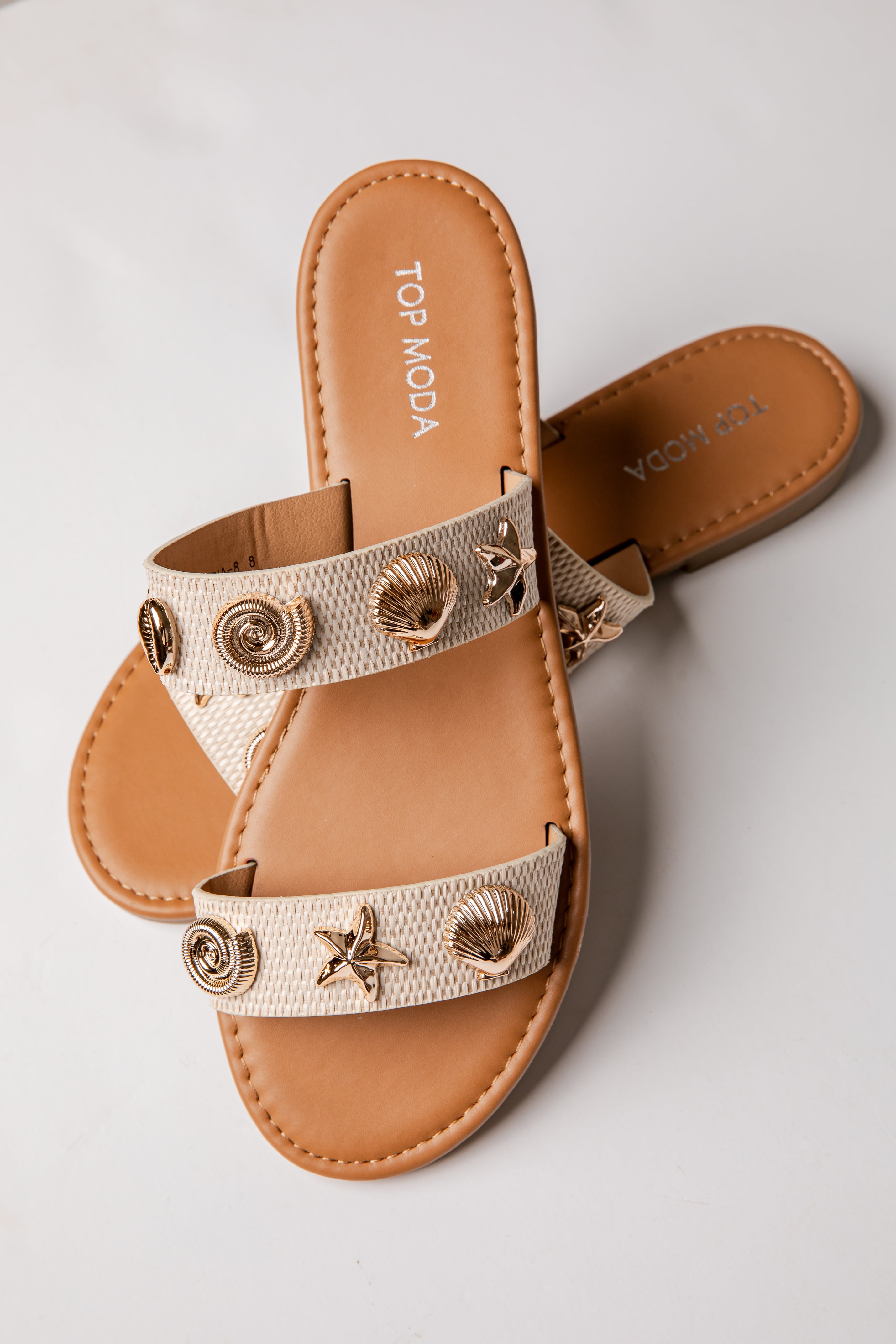 Beige sandal with decorative straps on a light gray background