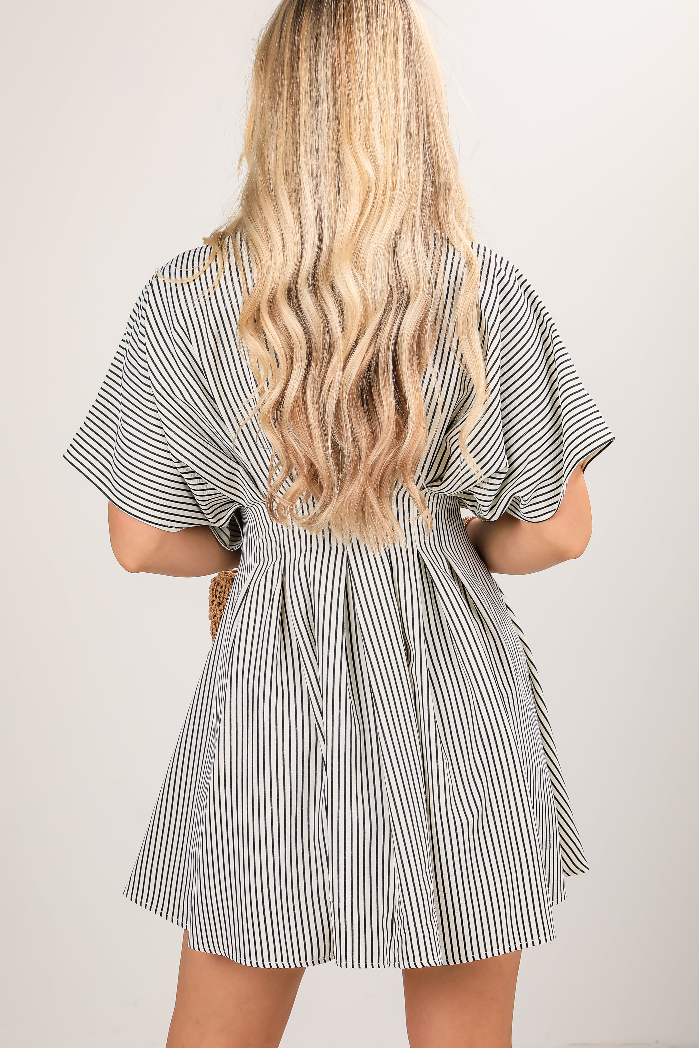 Woman wearing a black and white striped dress against a plain background