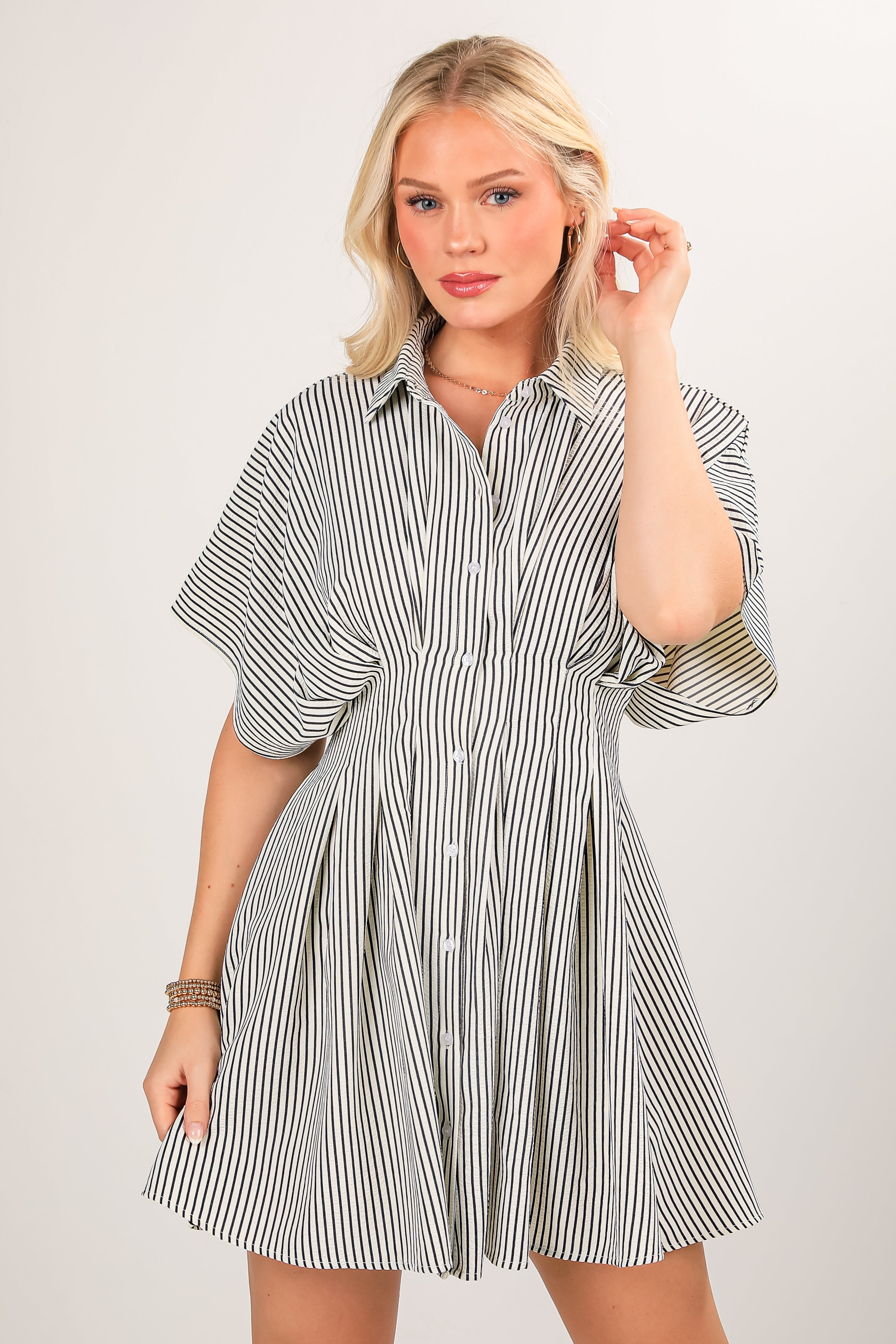 Woman wearing a black and white striped shirt dress on a plain background