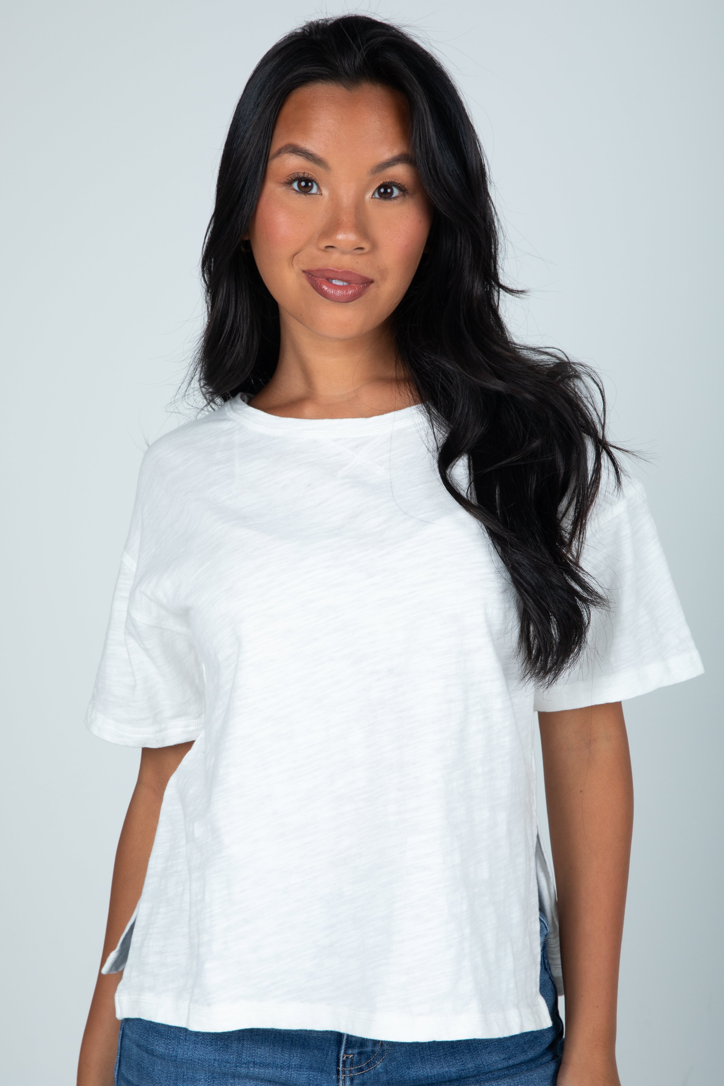Woman wearing a white t-shirt against a plain background