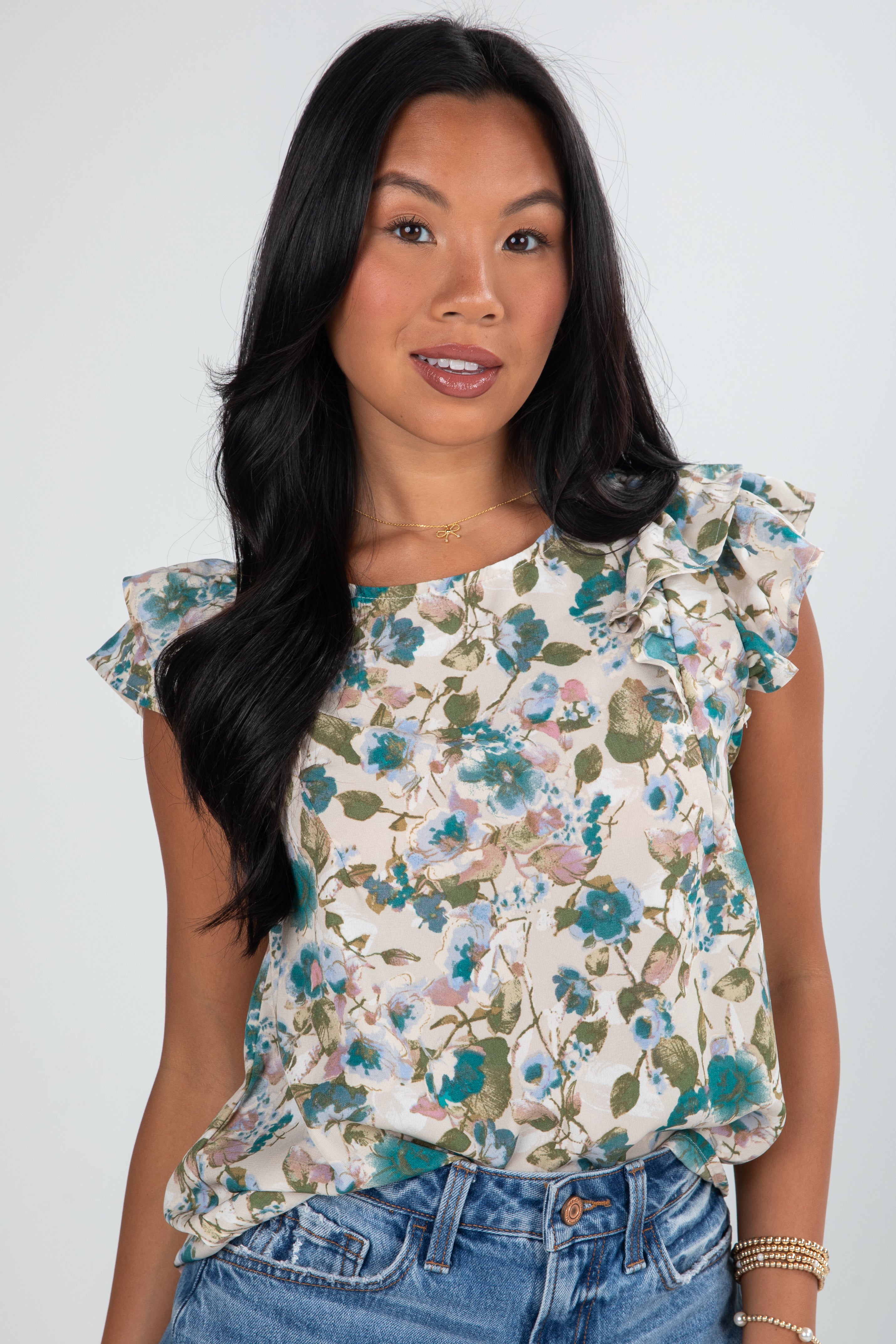 Woman wearing a floral blouse with ruffled sleeves against a white background