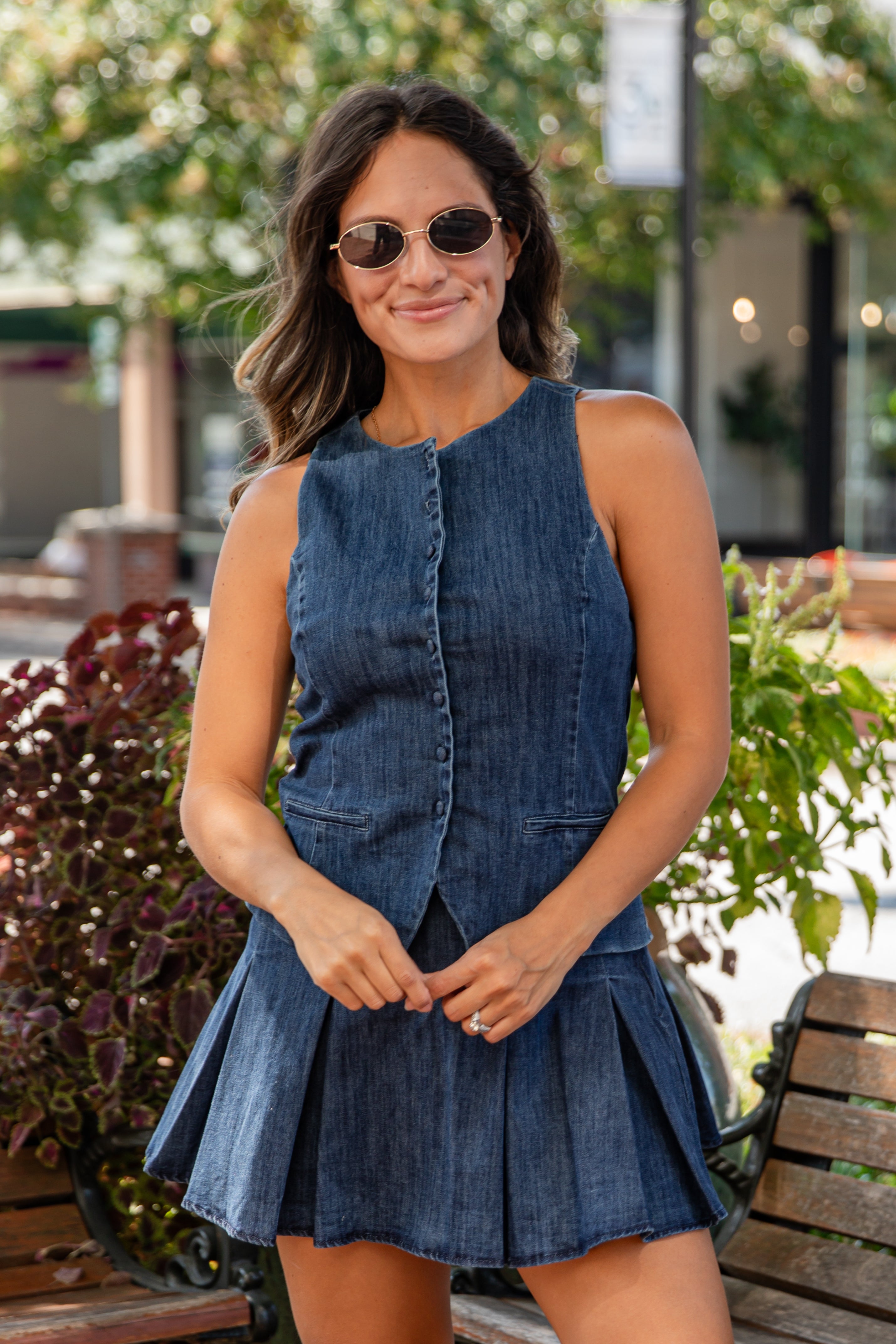 Woman wearing a blue denim dress and sunglasses outdoors.