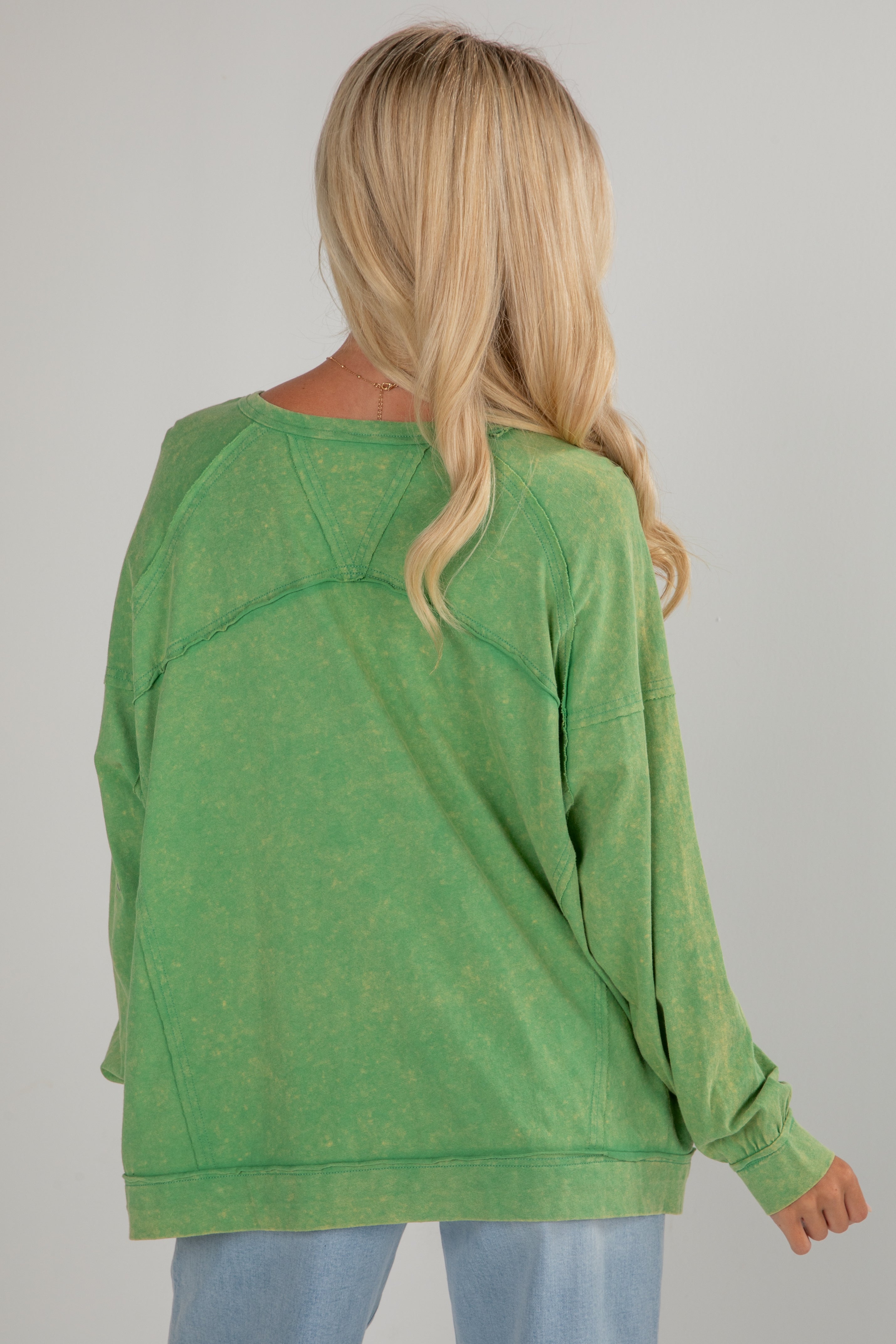 Person wearing a green sweater on a plain background