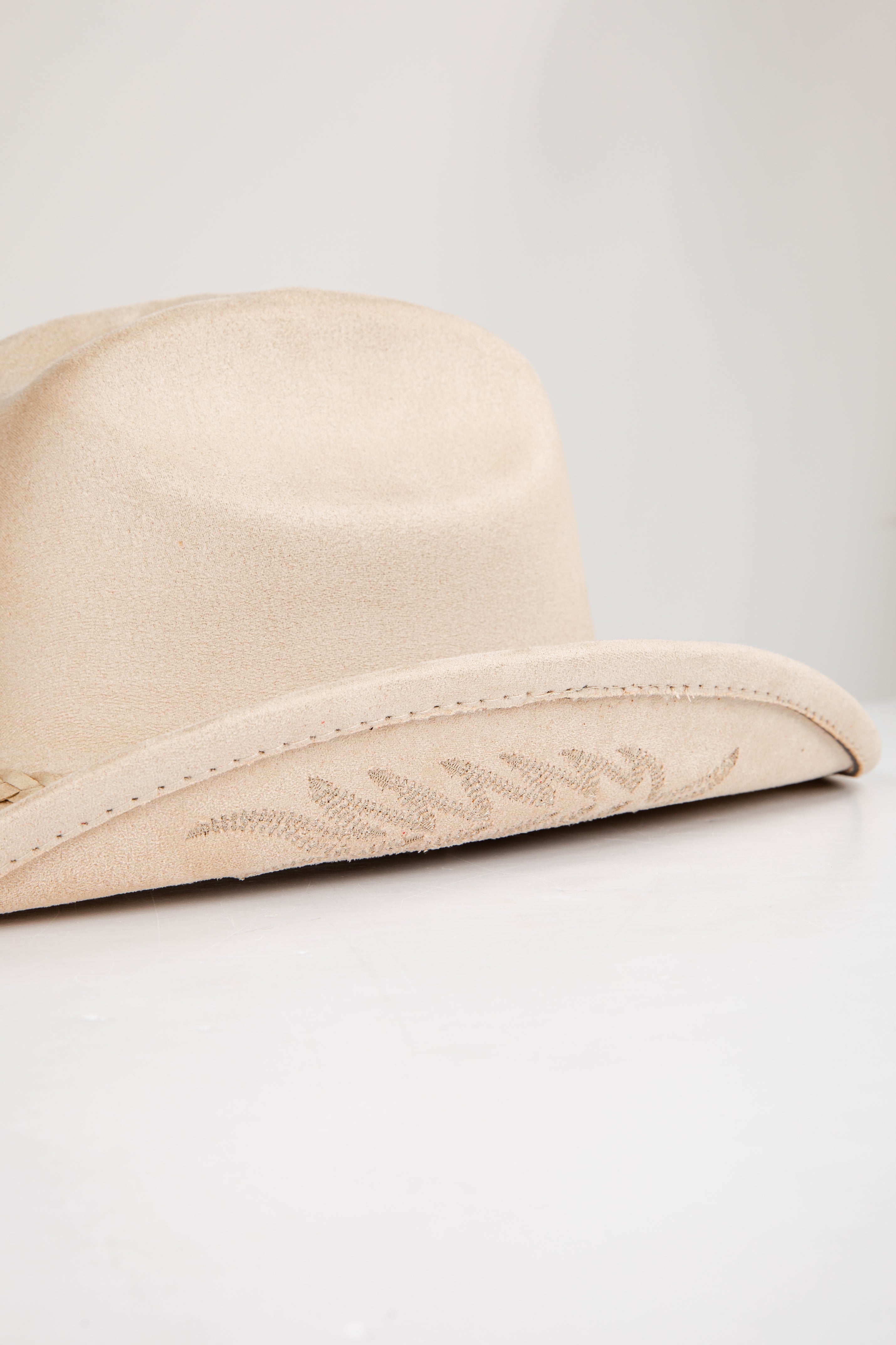 Beige hat with floral embroidery on a light gray background