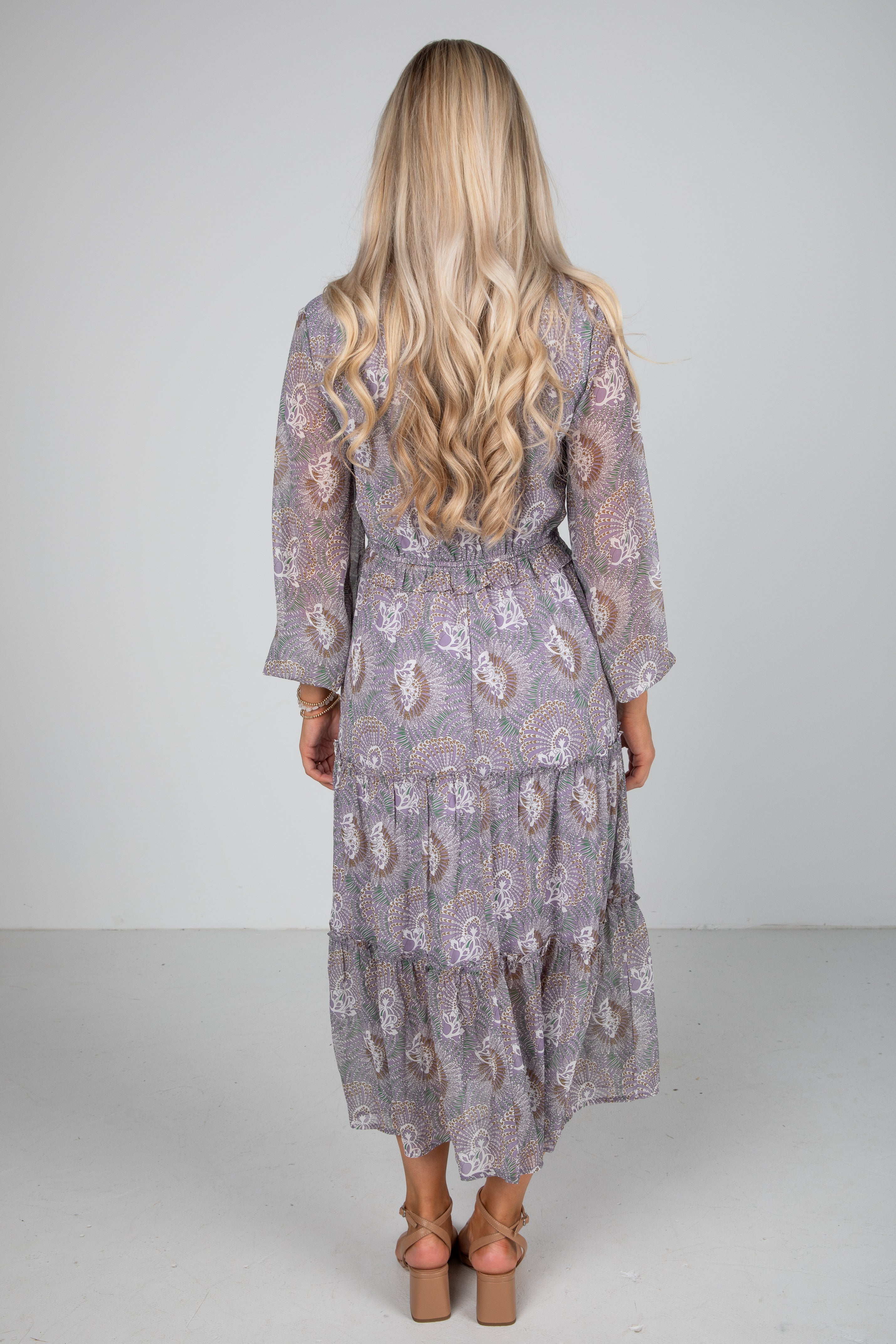 Woman wearing a patterned dress with long hair on a plain background