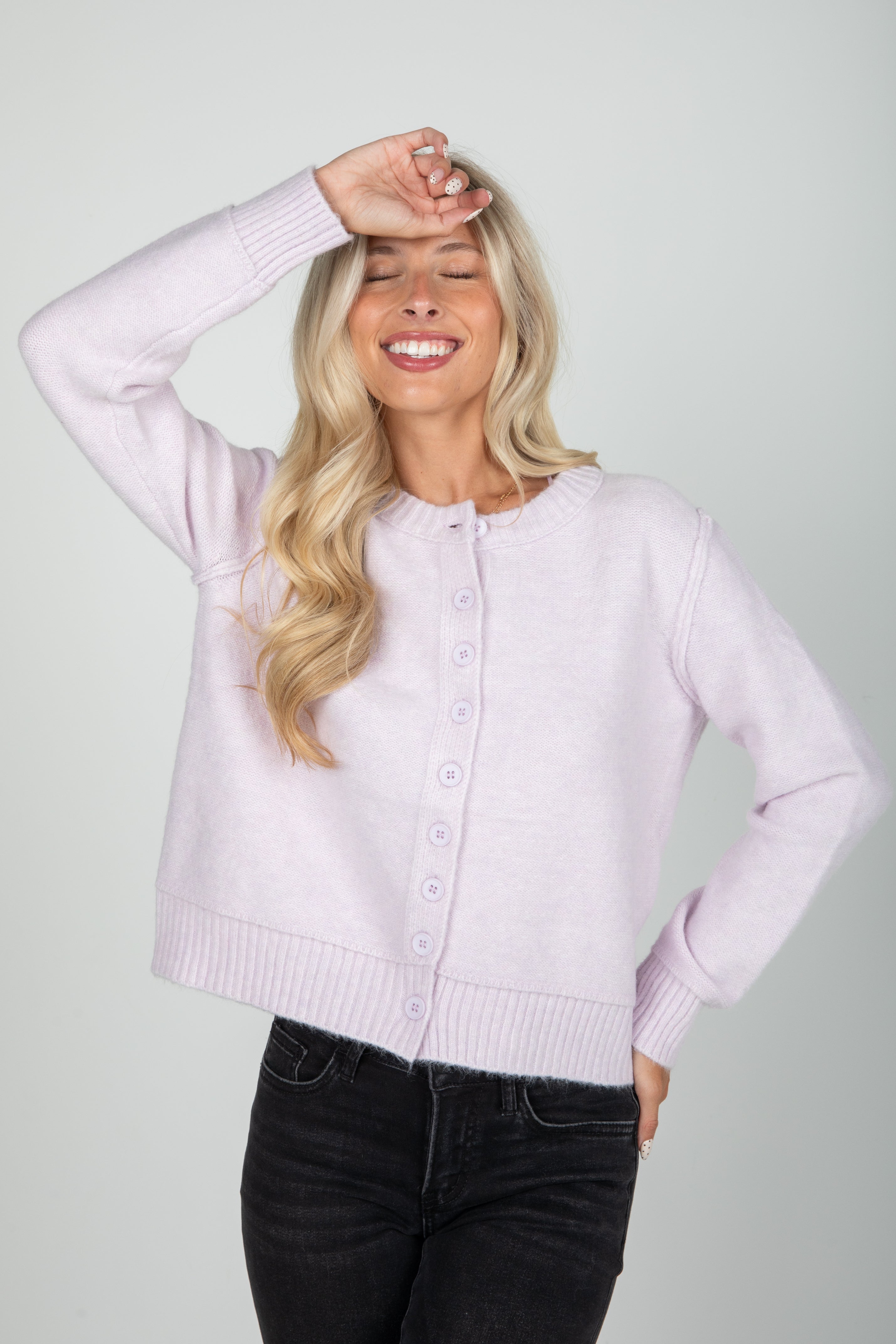 Woman wearing a light purple cardigan against a plain background